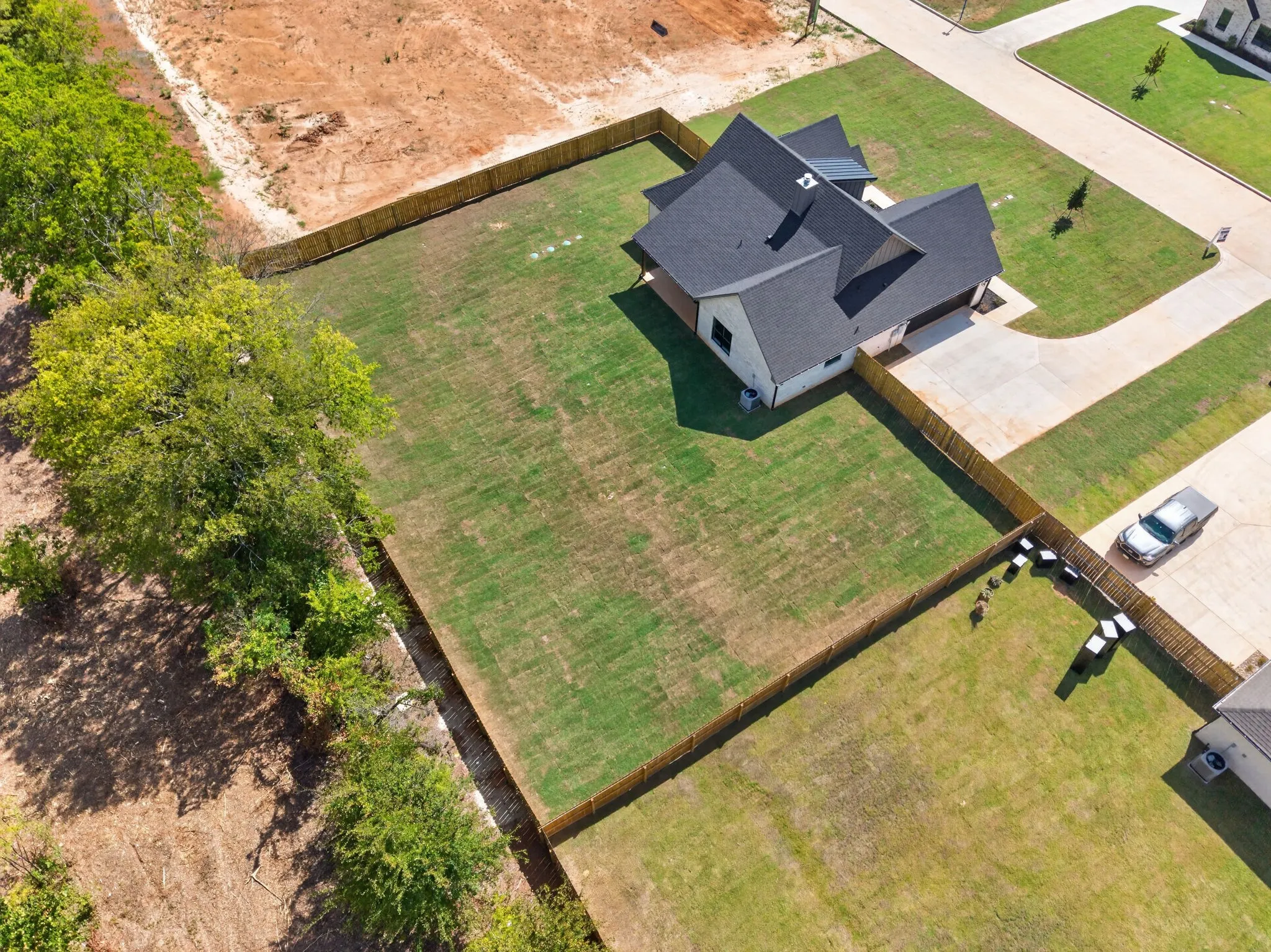 New construction residence featuring a dark shingle roof, light-colored exterior, and an expansive lawn