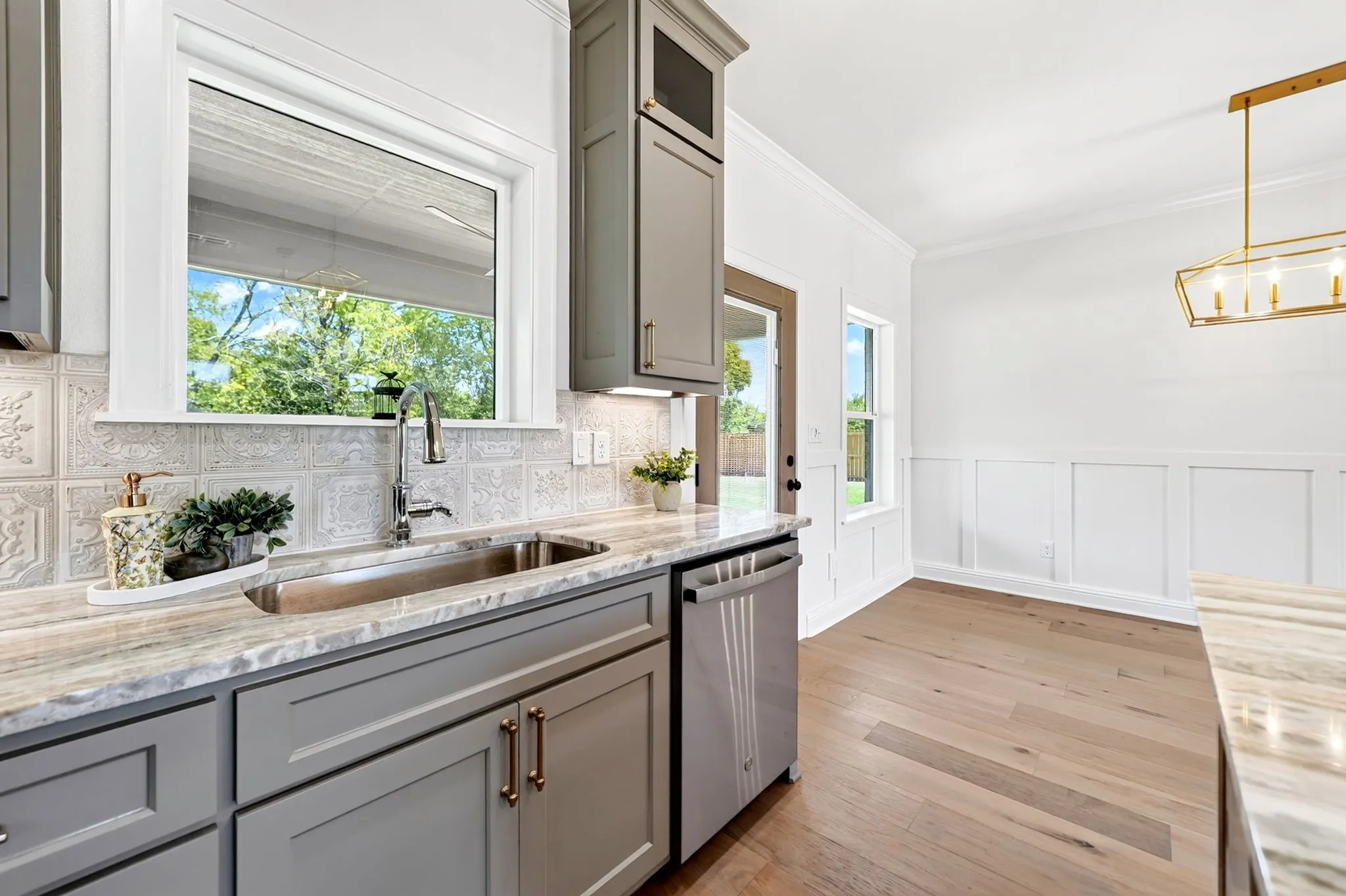 Kitchen featuring shaker-style cabinetry, a stainless steel sink, and a patterned tile backsplash