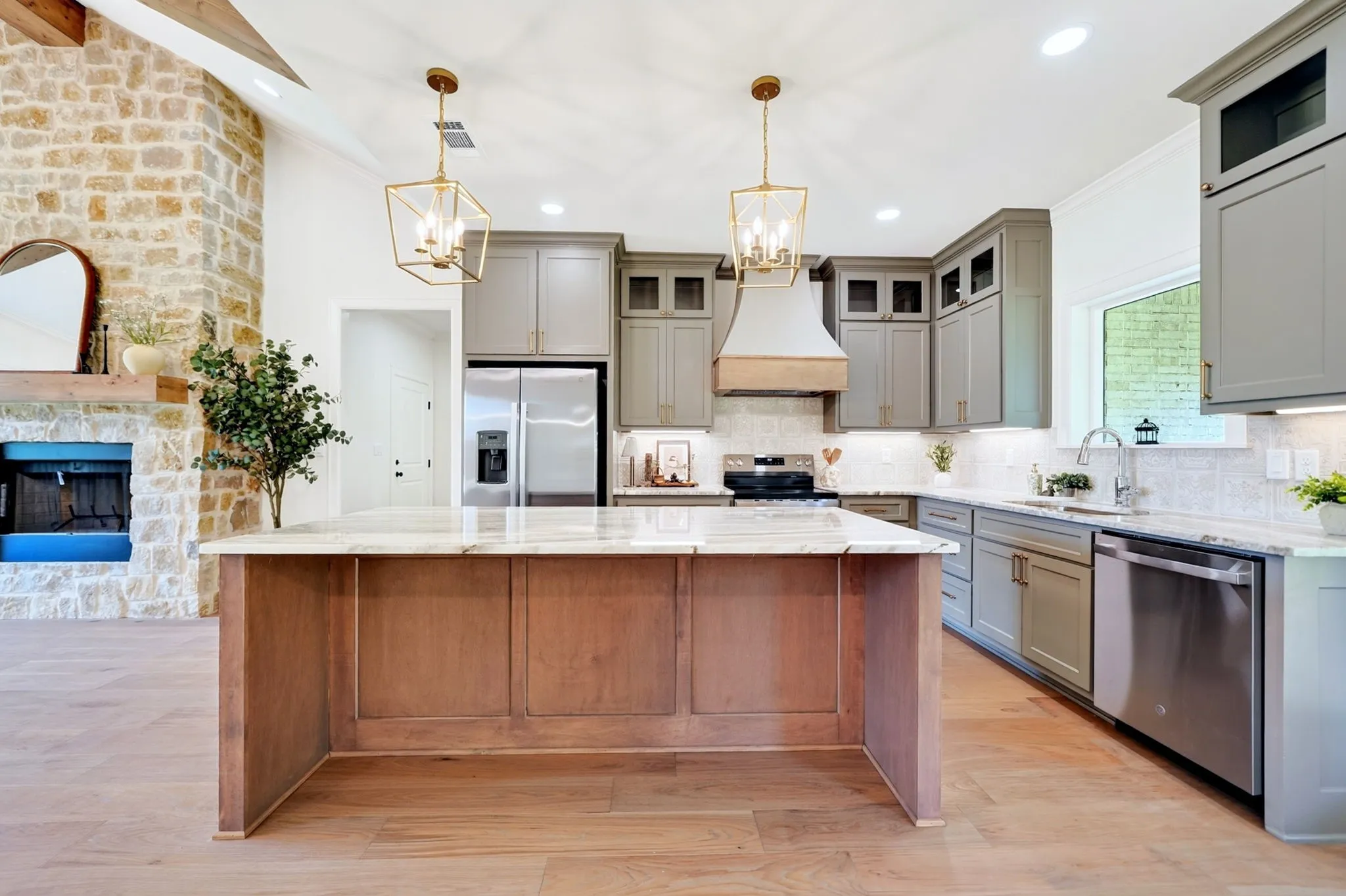 Kitchen featuring a large central island with a light-toned countertop, light wood-finish flooring, recessed lighting, and stainless steel appliances