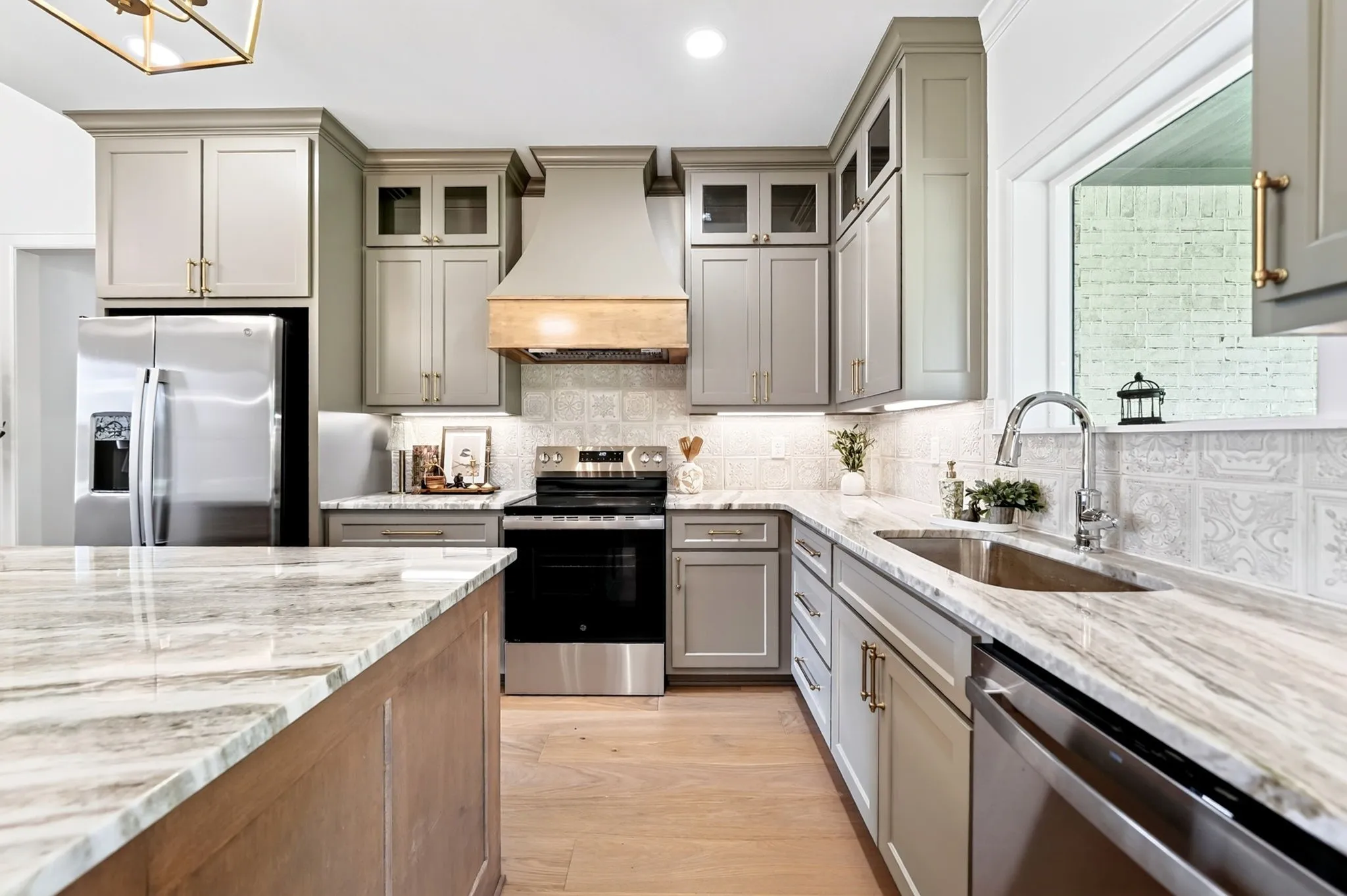 Kitchen featuring wood-finish flooring, light-toned cabinetry, stainless steel appliances, and stone countertops