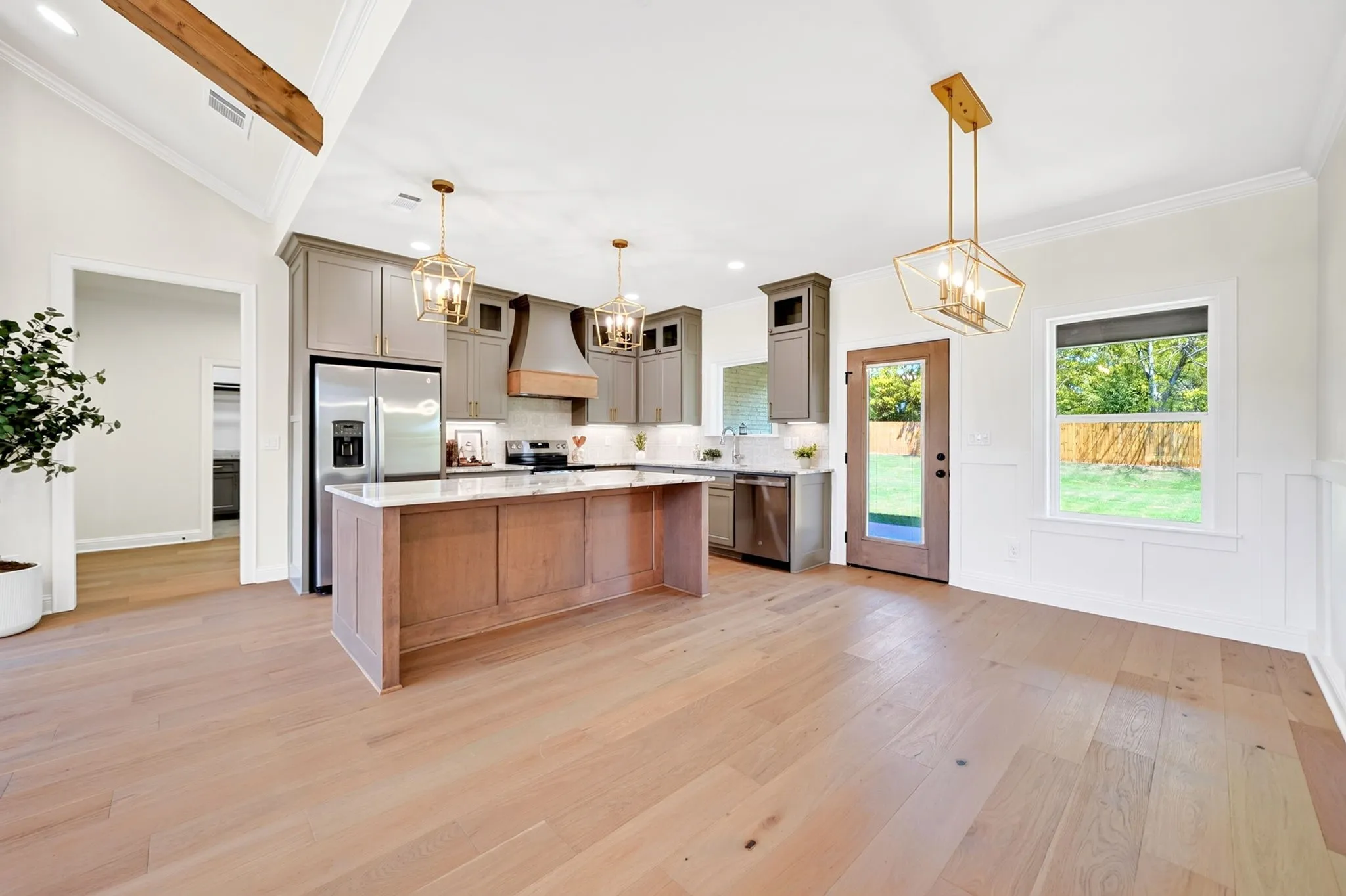 Open concept kitchen and dining area featuring wood-finish flooring, a kitchen island with stone countertop, stainless steel appliances, and ceiling-mounted light fixtures