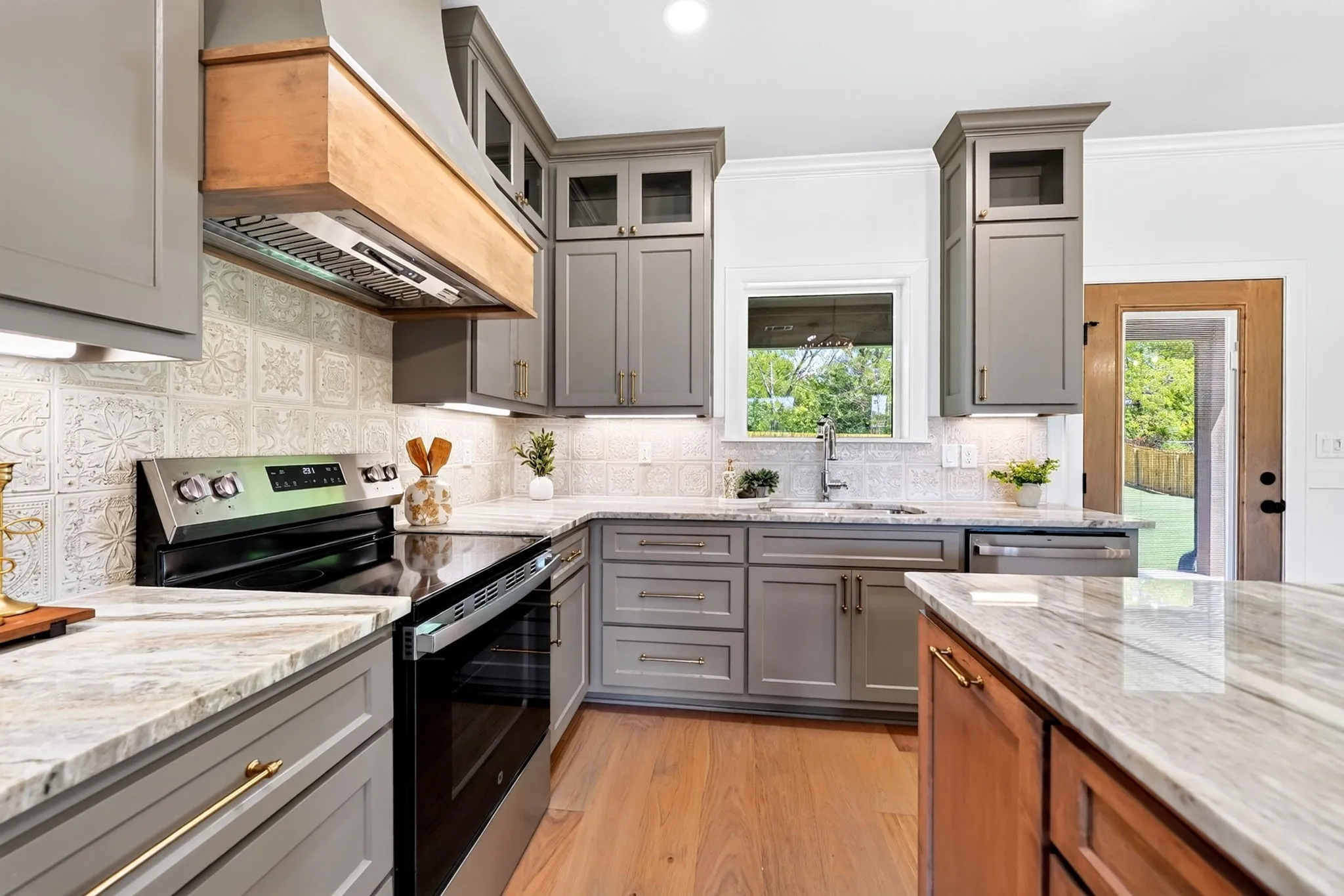 Kitchen featuring gray shaker-style cabinetry, light-toned countertops, tile backsplash, and stainless steel appliances