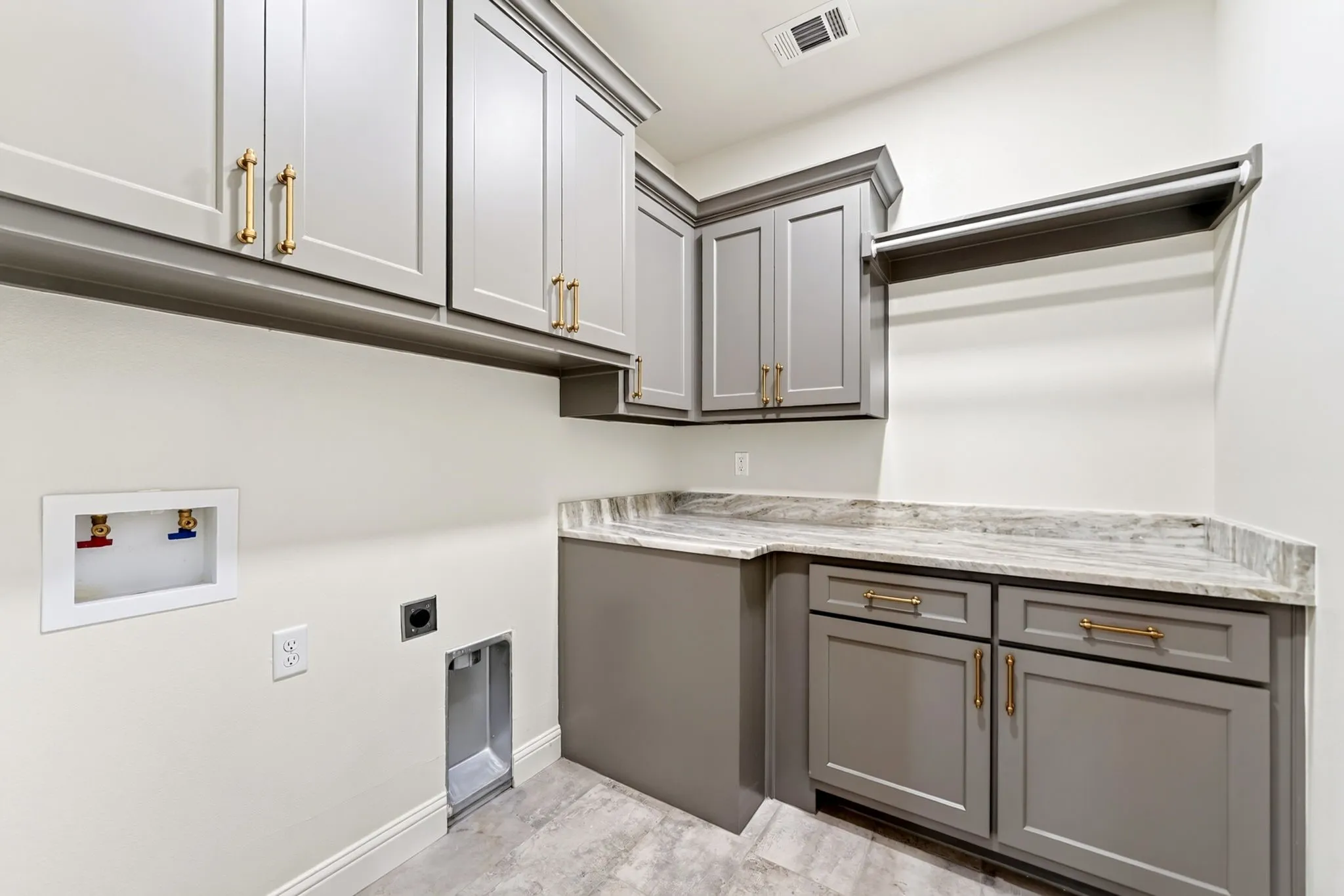 Shaker-style cabinetry with gold-tone hardware, a light-toned countertop, and integrated hanging rod