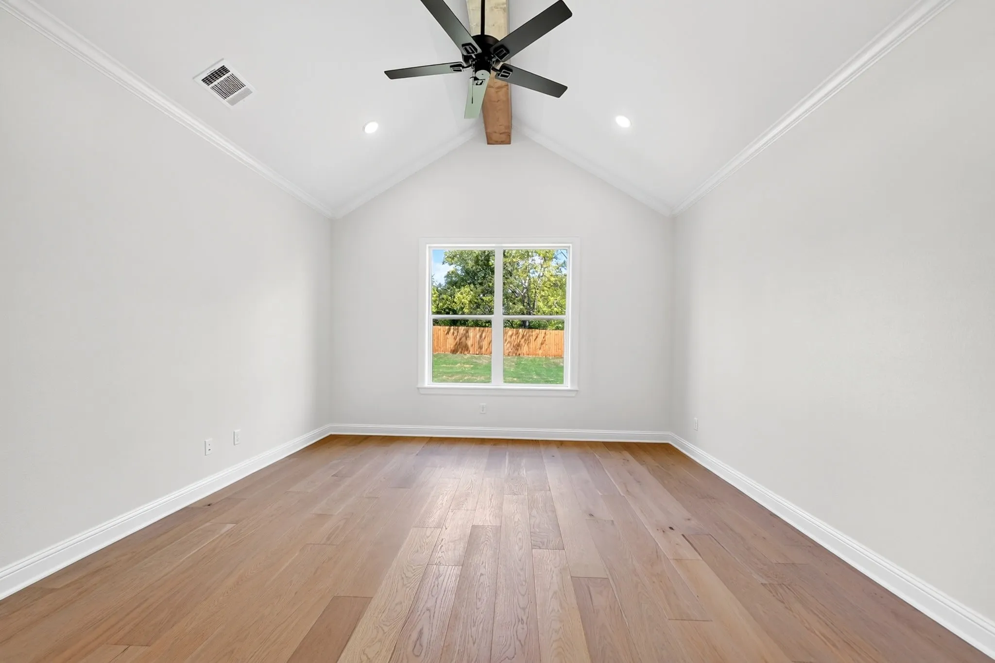 Vaulted ceiling, wood-finish flooring, recessed lighting, ceiling fan, and a window with exterior views