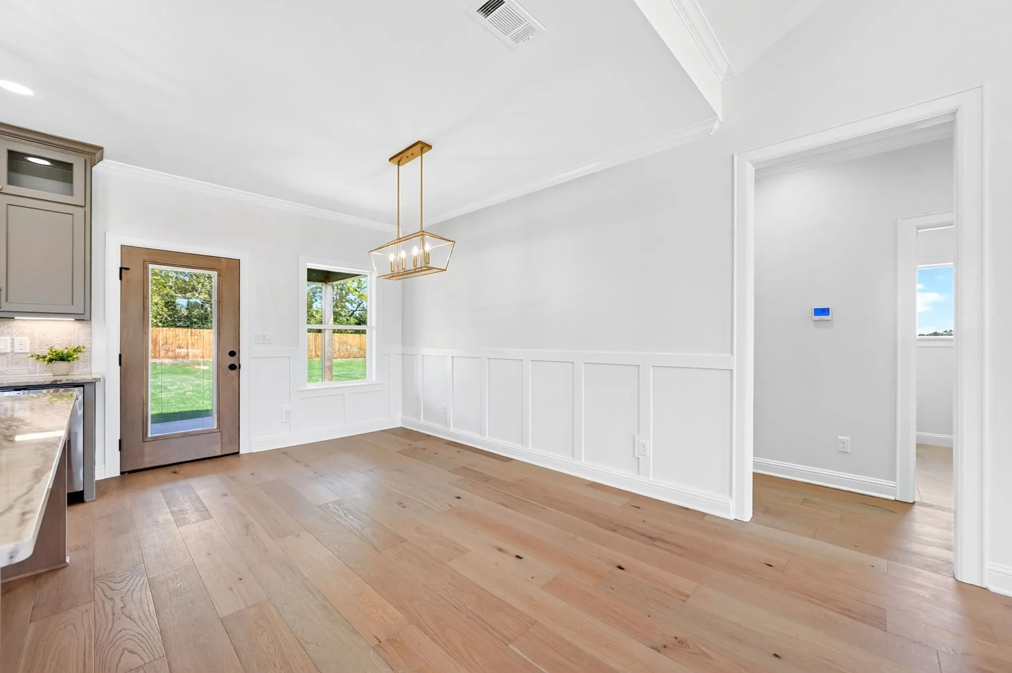 Wood-finish flooring throughout, board and batten wall detailing, crown molding, and a gold-finish chandelier