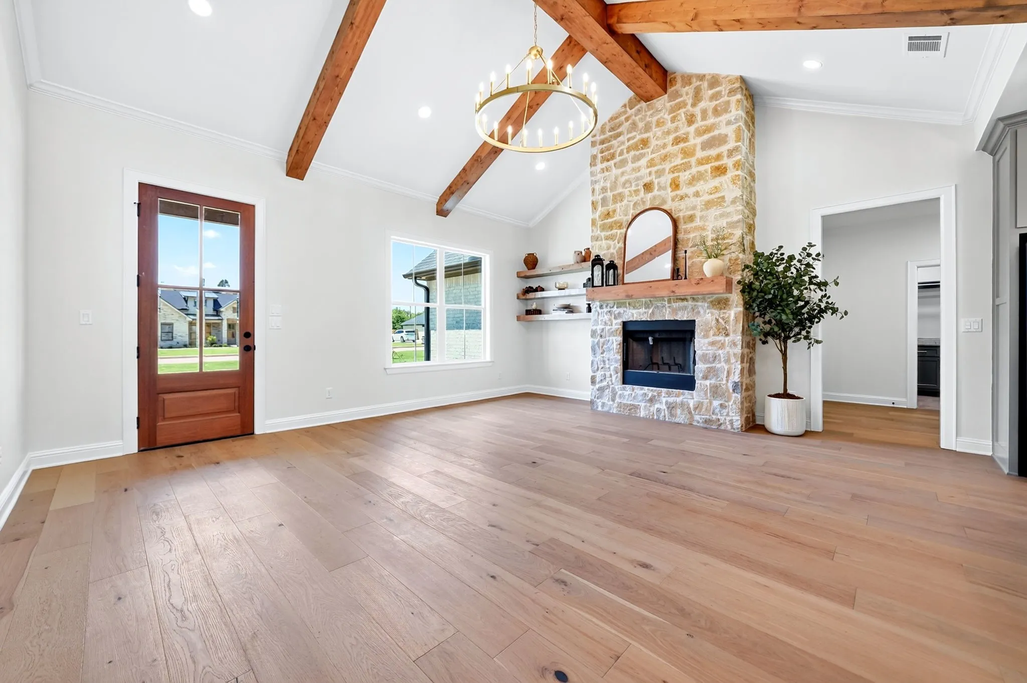 Vaulted ceiling with exposed wood beams, stone fireplace, wood-finish flooring, and recessed lighting
