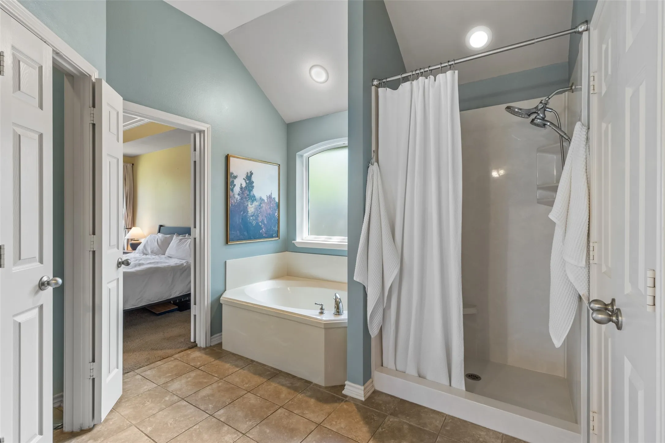Corner soaking tub, separate shower with tiled surround, vaulted ceiling, recessed lighting, and tile flooring