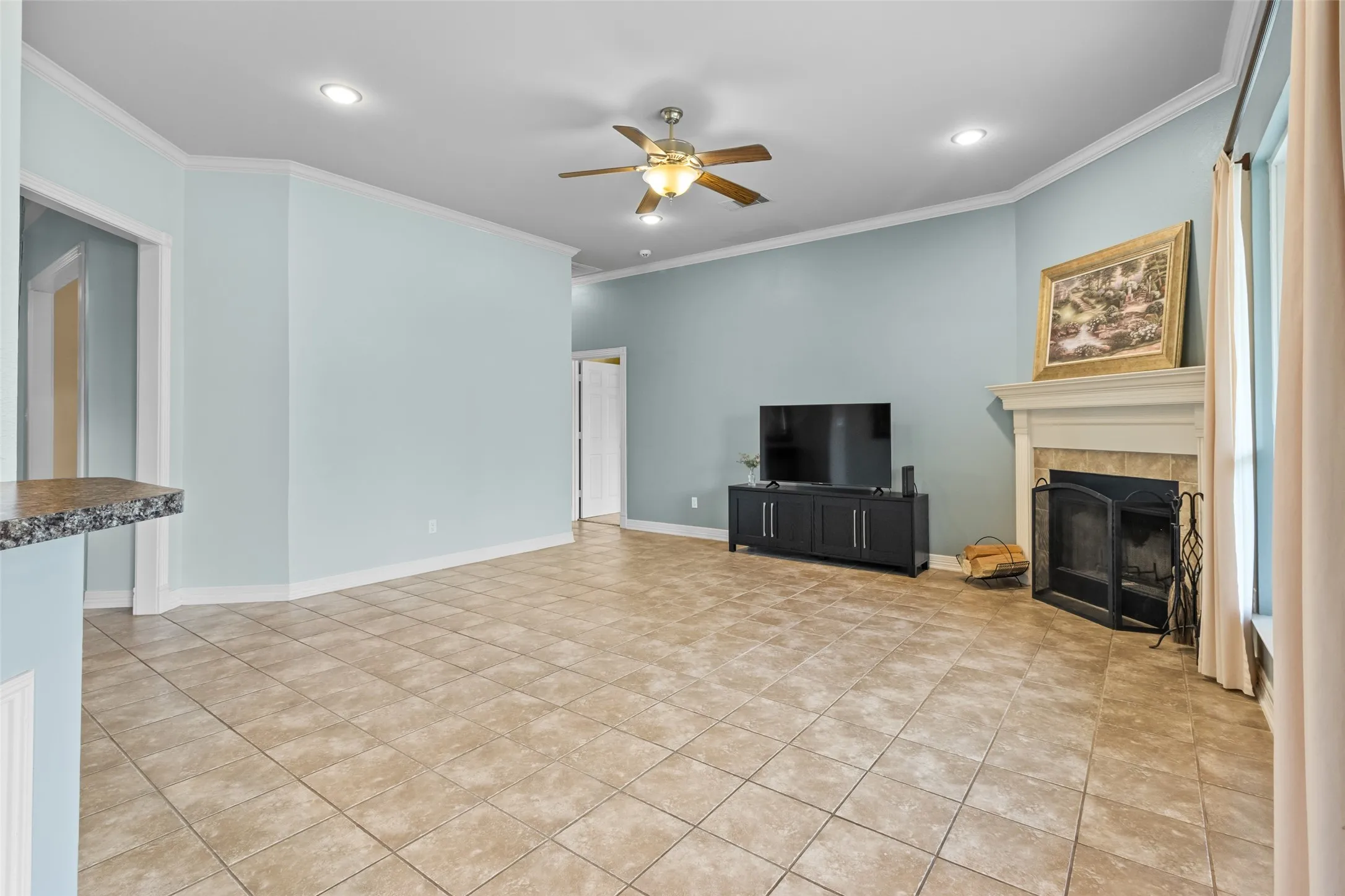 Spacious interior featuring tile flooring, a fireplace with a mantel, recessed lighting, and a ceiling fan