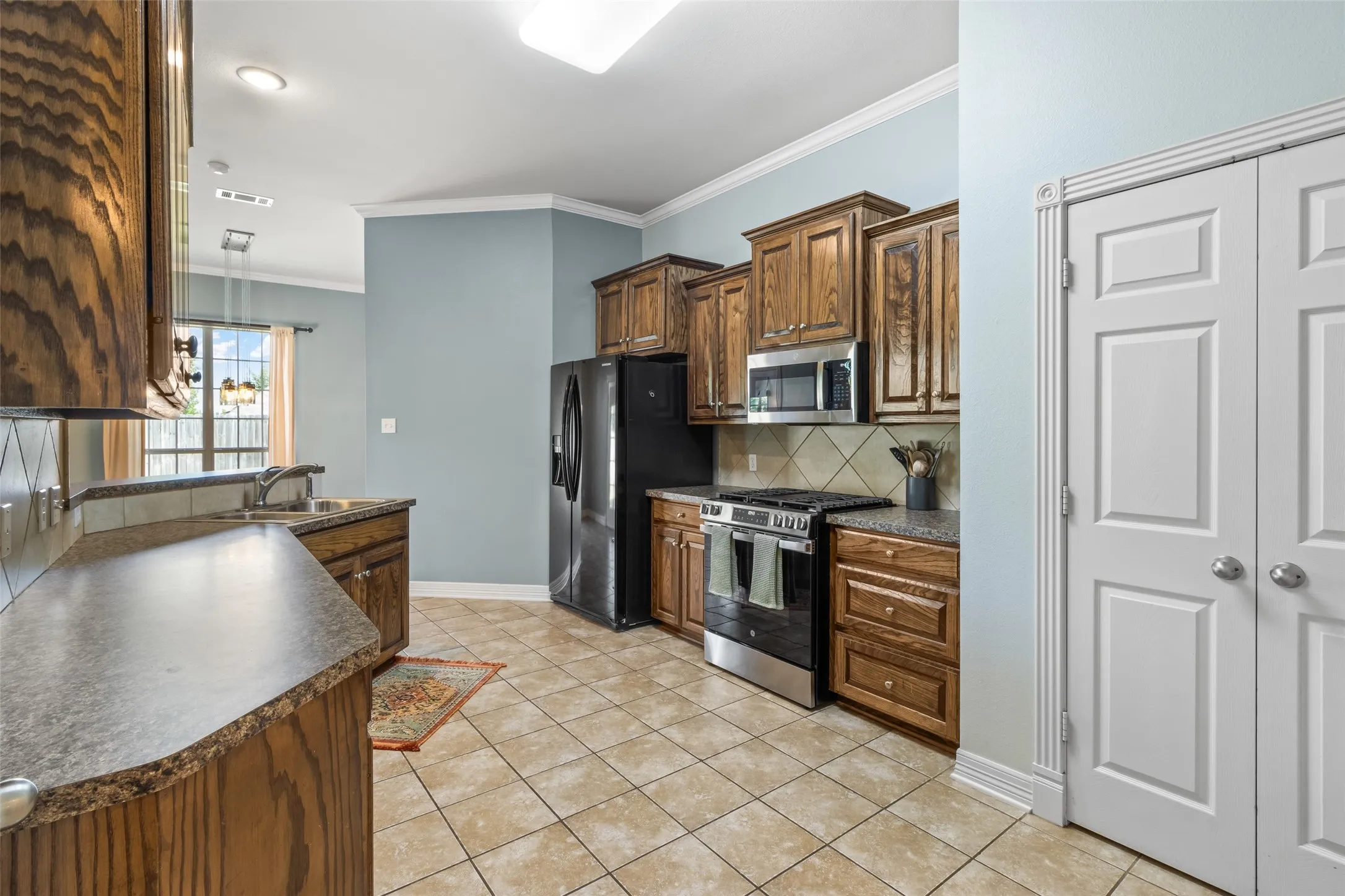 Kitchen featuring wood-finish cabinetry, tile flooring, and integrated black appliances
