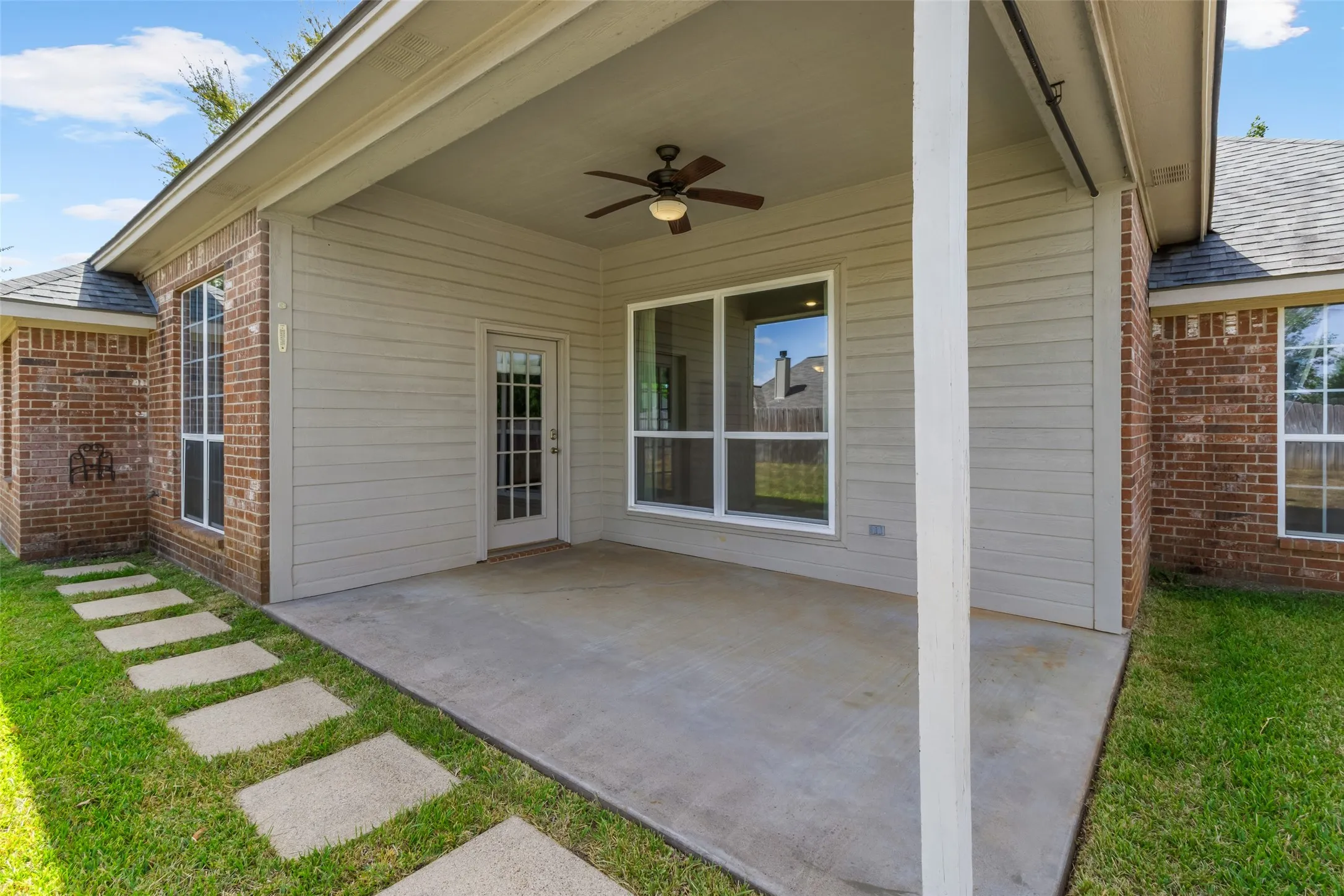 Covered patio featuring a ceiling fan, concrete flooring, and an exterior door