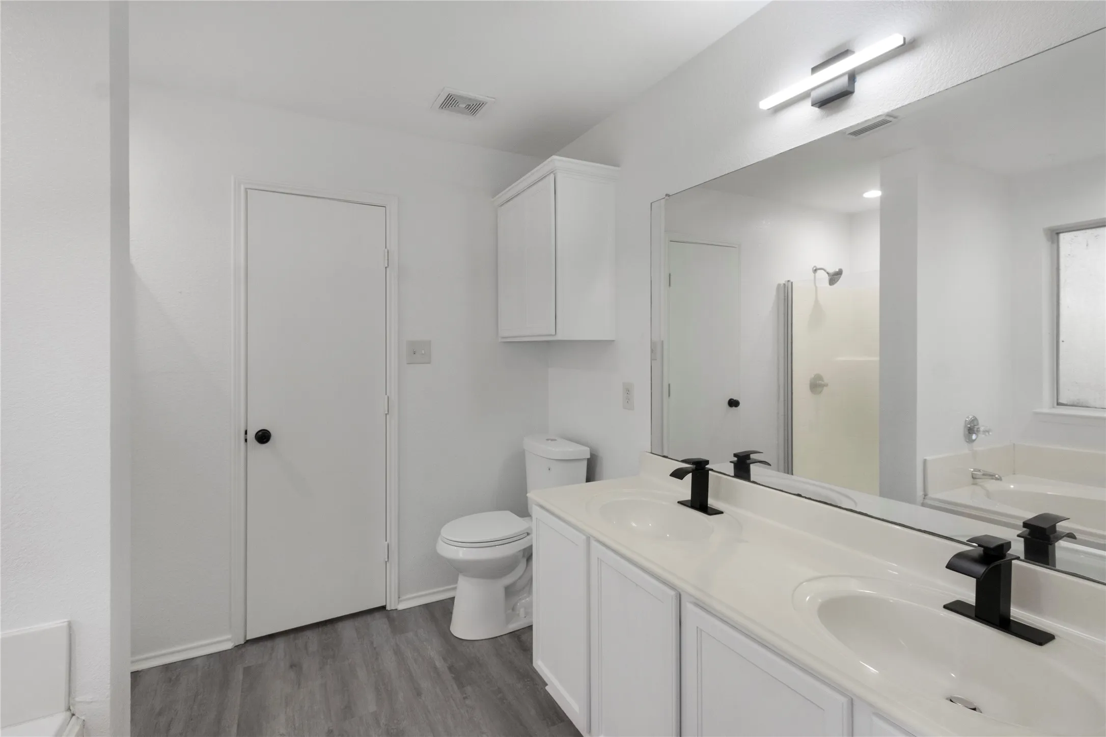 Bathroom featuring a dual vanity with undermount sinks, matte black faucets, and a large wall-mounted mirror