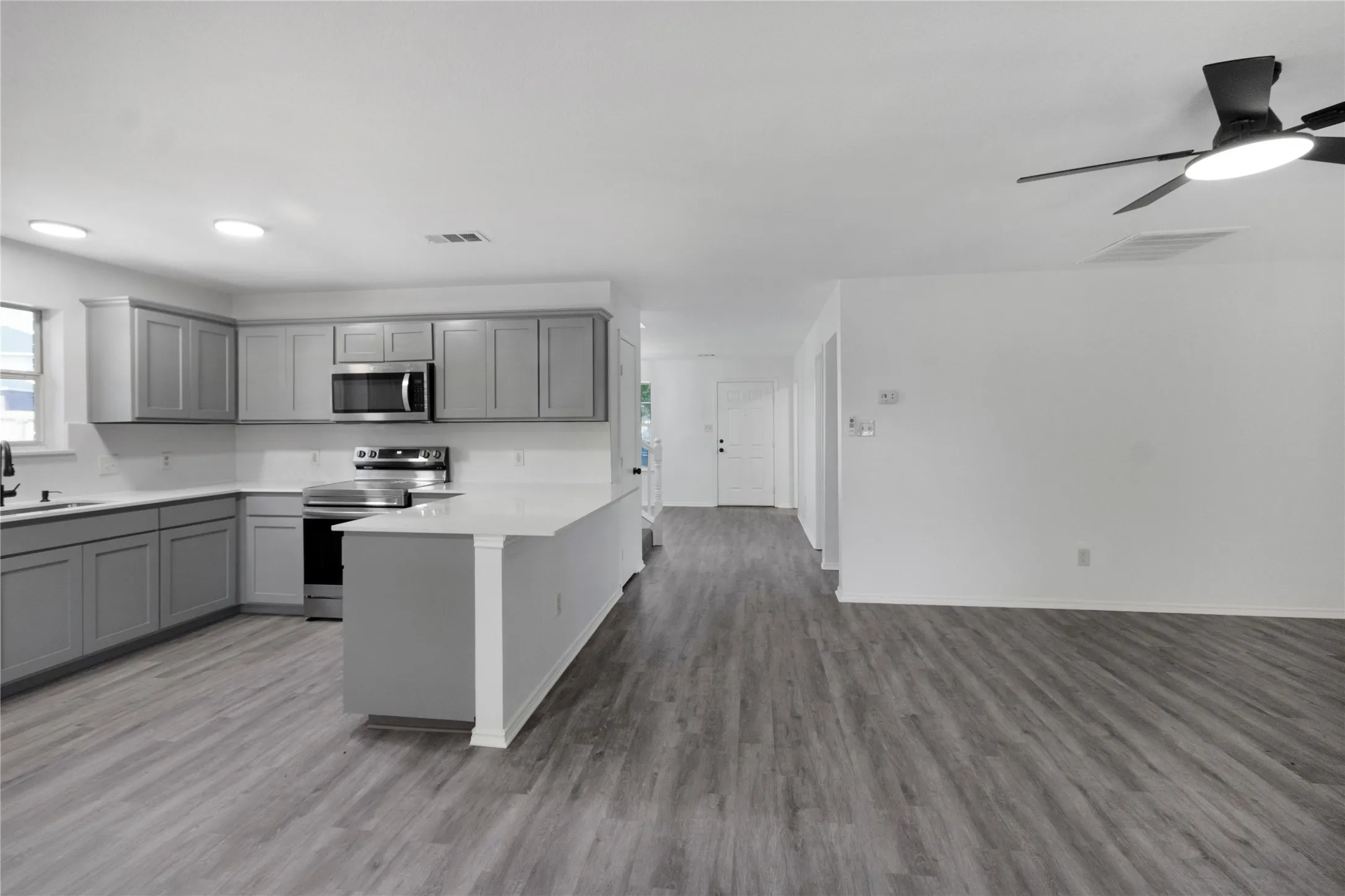 Open-concept living space with wood-finish flooring, recessed lighting, and a ceiling fan