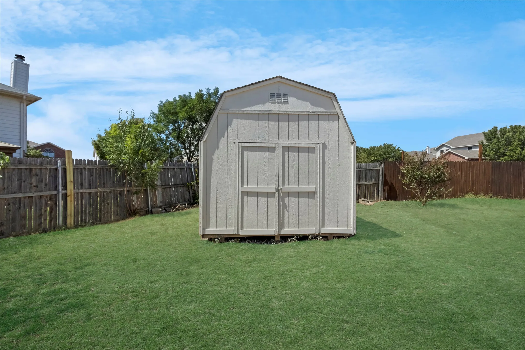 Expansive lawn featuring a storage shed with double doors and a gable roof