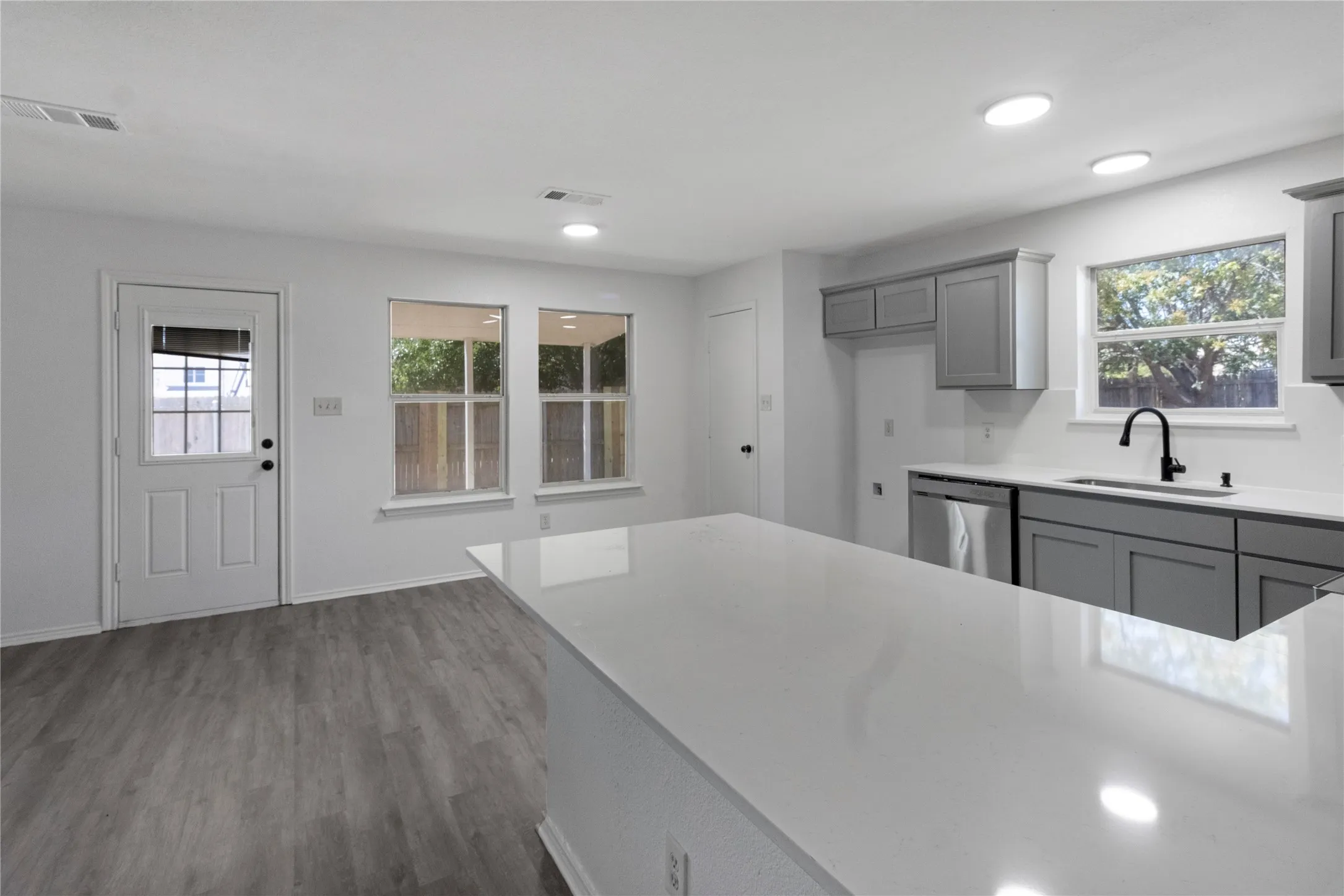 White quartz countertops, wood-finish flooring, recessed lighting, gray cabinetry, and a black gooseneck faucet