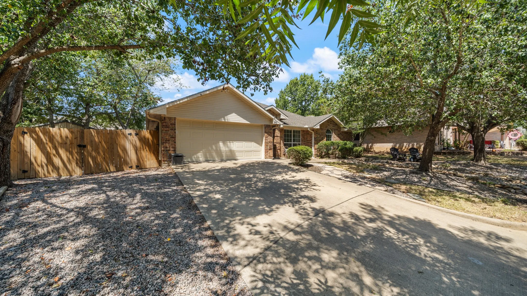 Brick and siding exterior with an attached garage, concrete driveway, and a wood fence