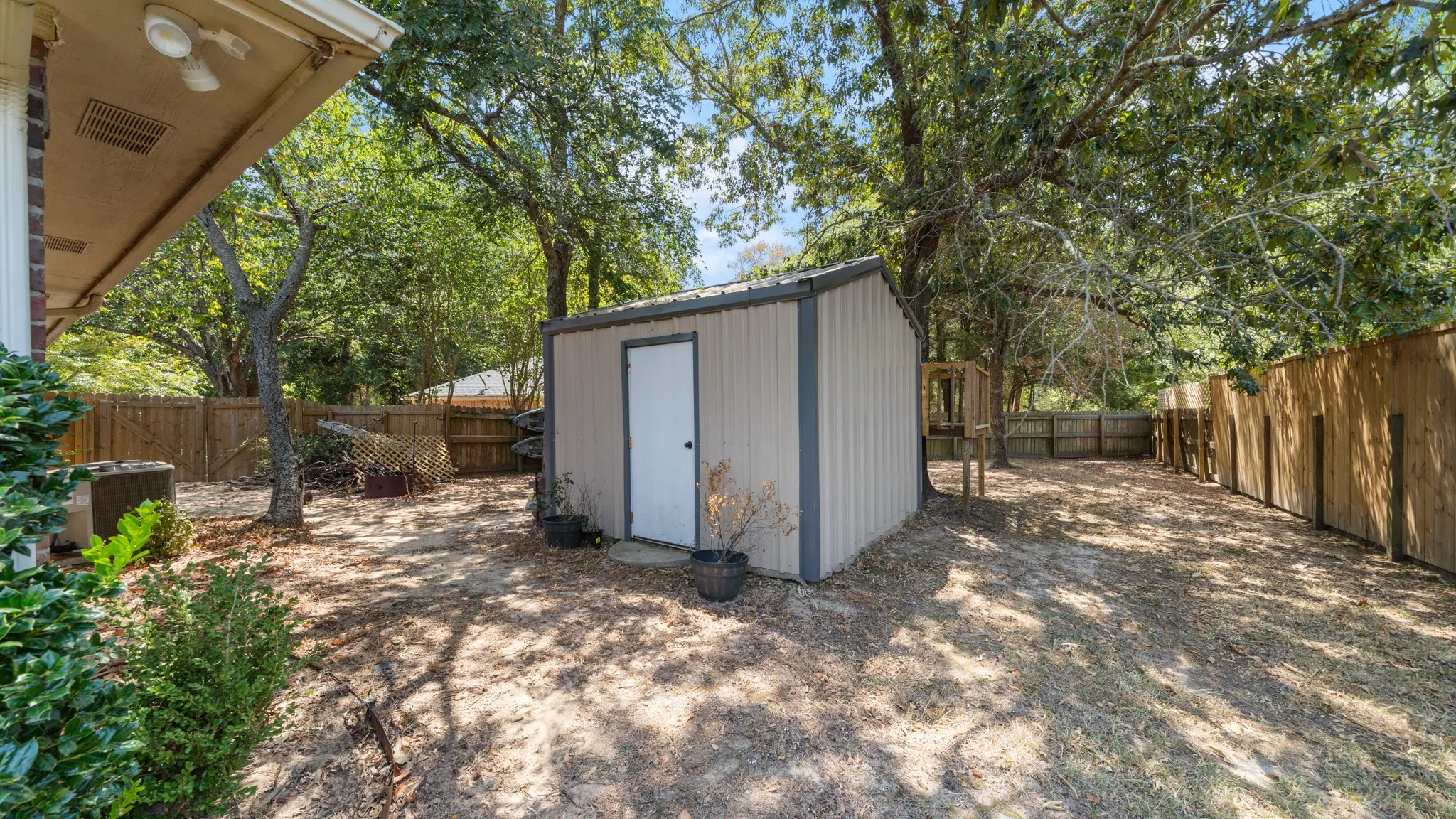 Private backyard with wood fencing, mature trees, and a metal storage shed