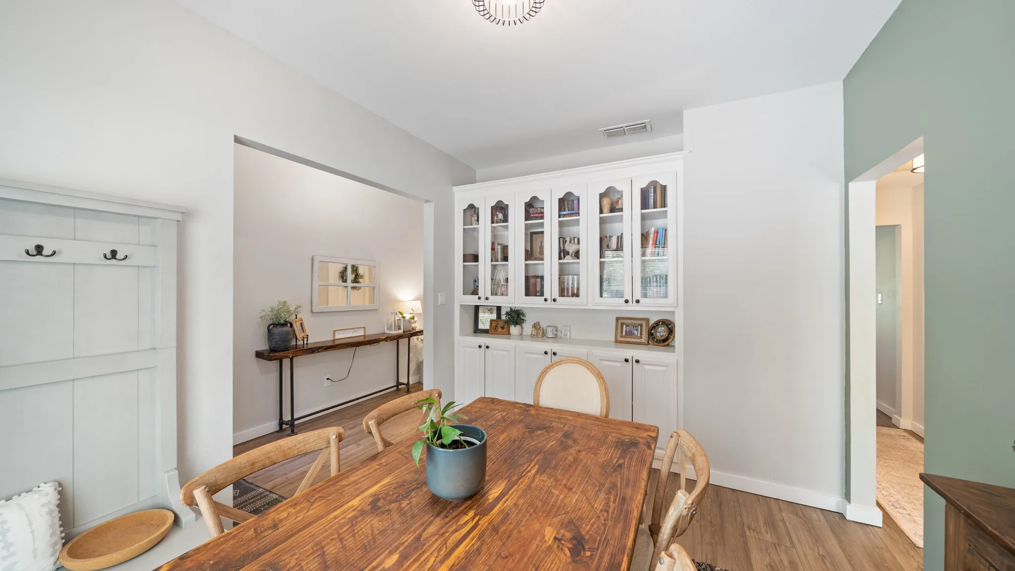 Built-in cabinetry with glass-front doors, wood-finish flooring, and a decorative ceiling light fixture