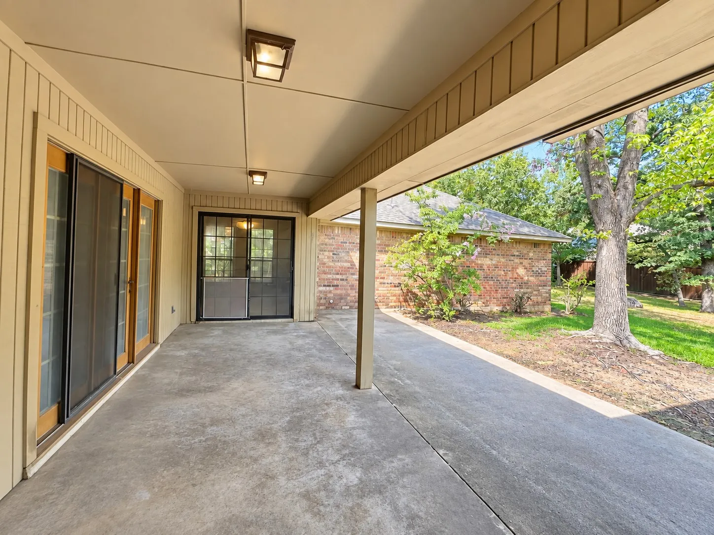 Covered concrete patio with two flush-mount lighting fixtures