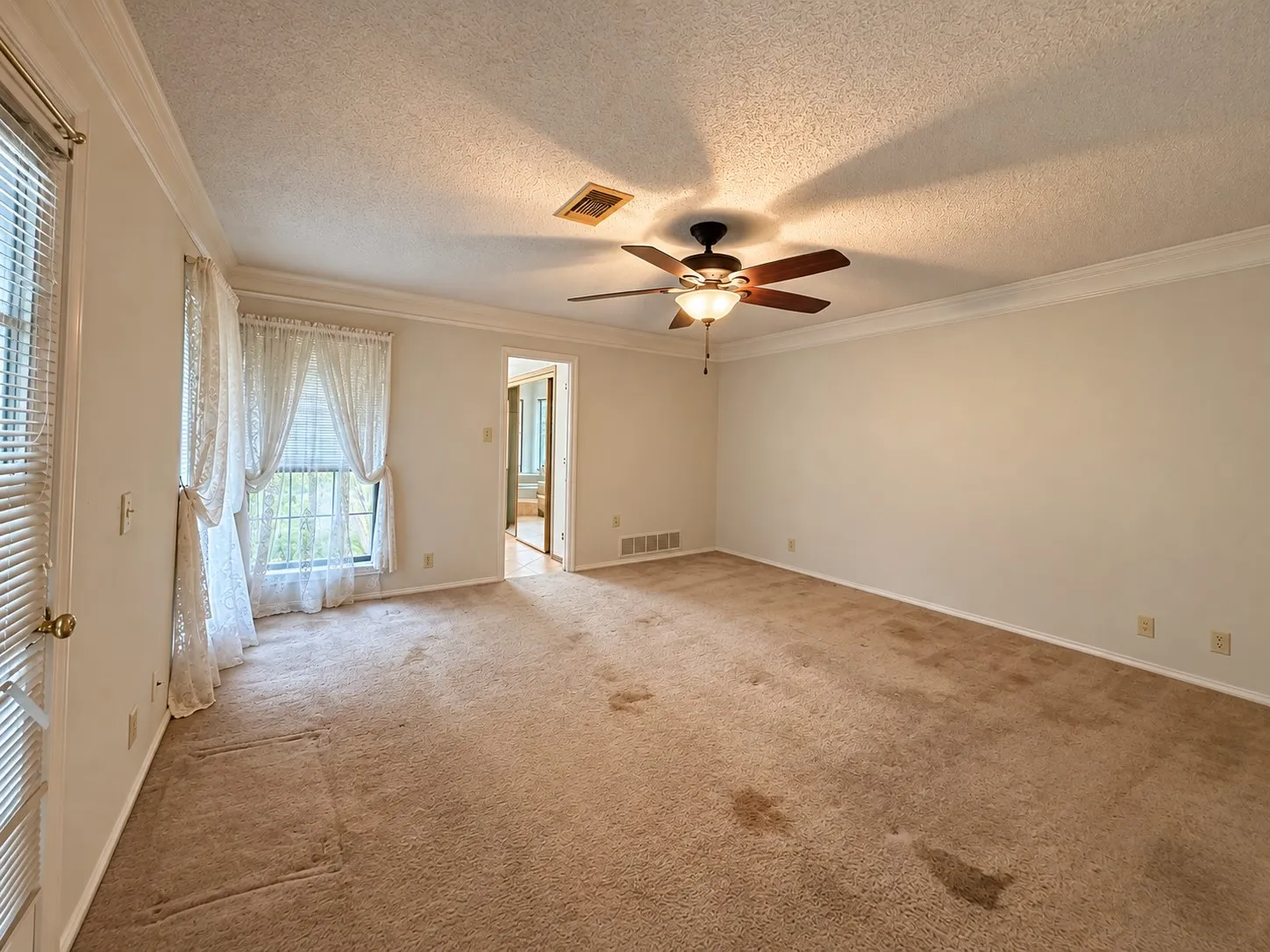 Primary bedroom with recessed window with blinds, ceiling fan with light fixture, crown molding, and wall-to-wall carpeting