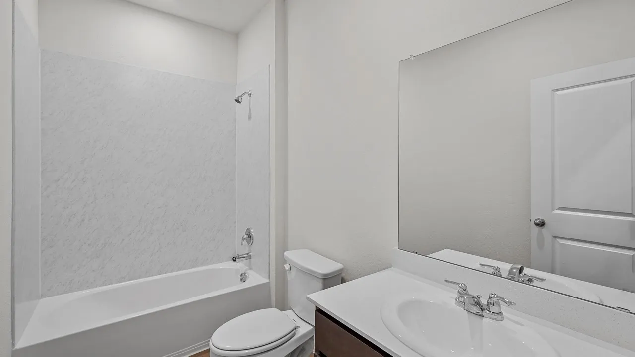 Bathroom featuring a white bathtub, shower with a chrome showerhead, single vanity with an integrated sink, and an expansive wall mirror