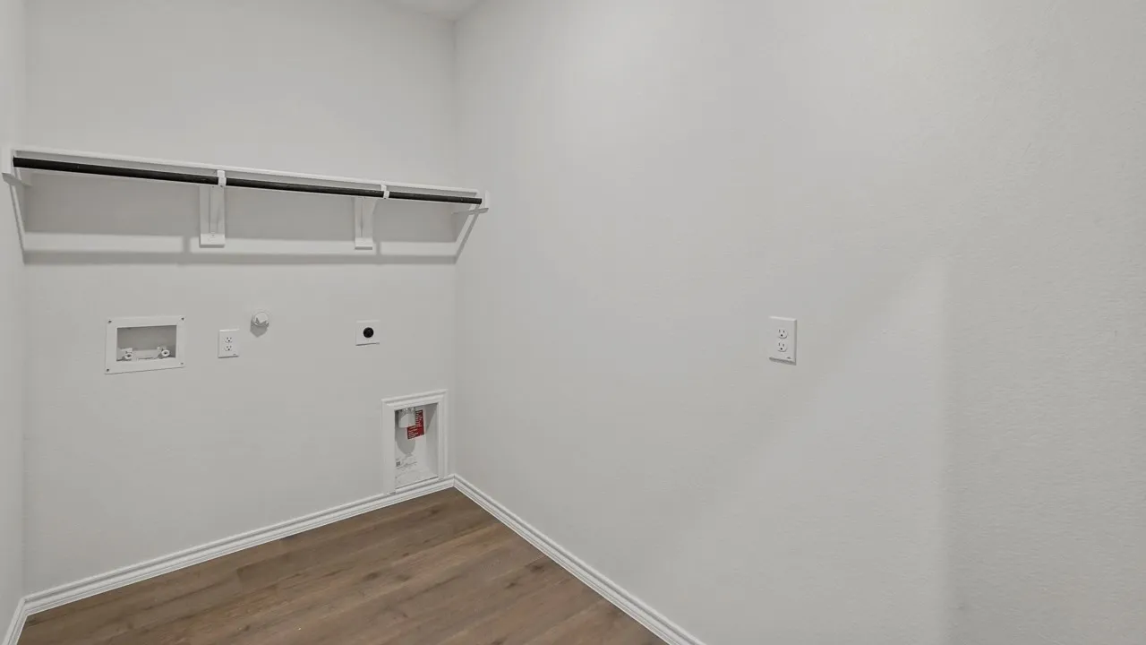 Laundry area with wood-finish flooring, white walls, and a built-in shelving unit with a hanging rod