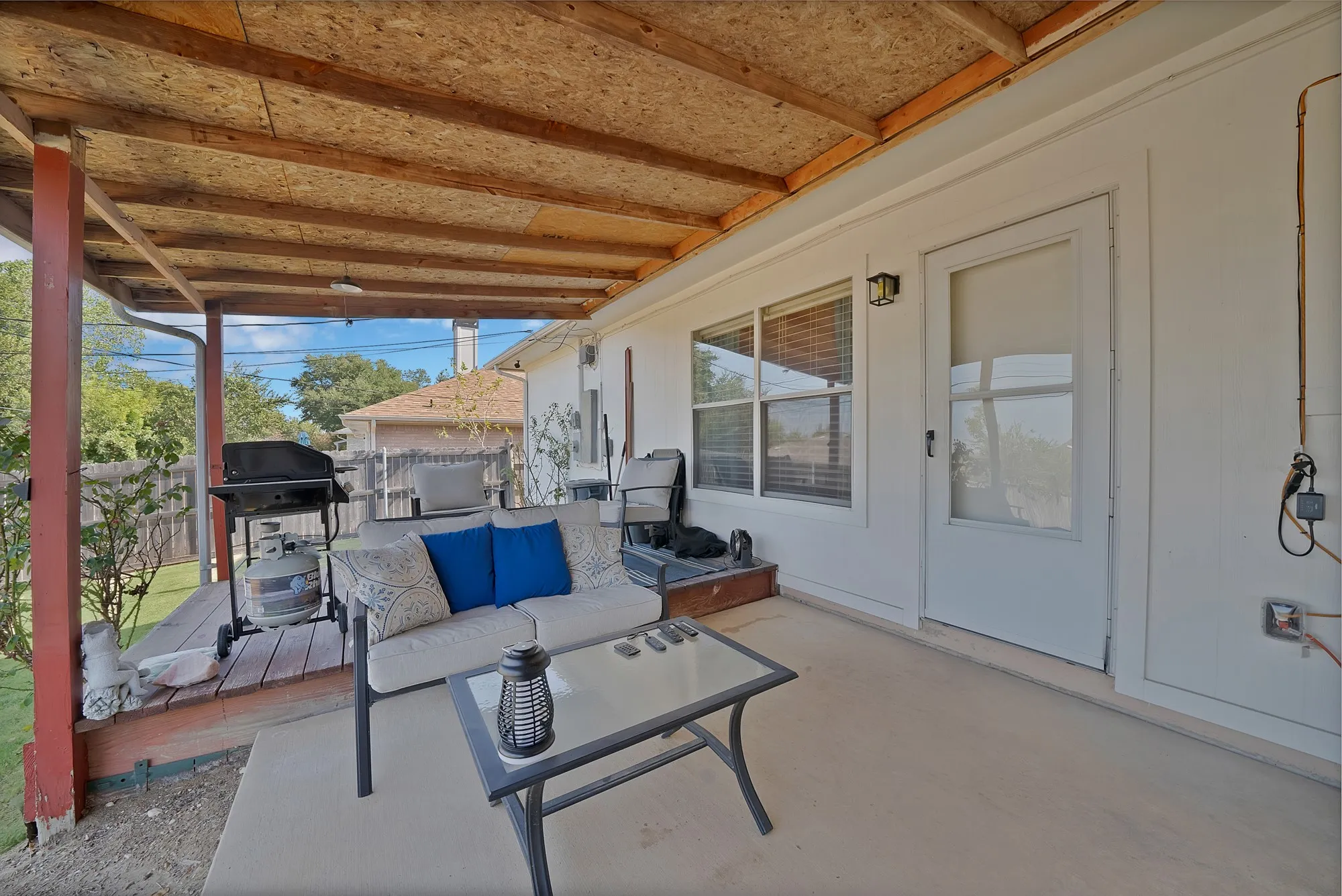 Covered patio with a wood-finish ceiling, exterior door, and window