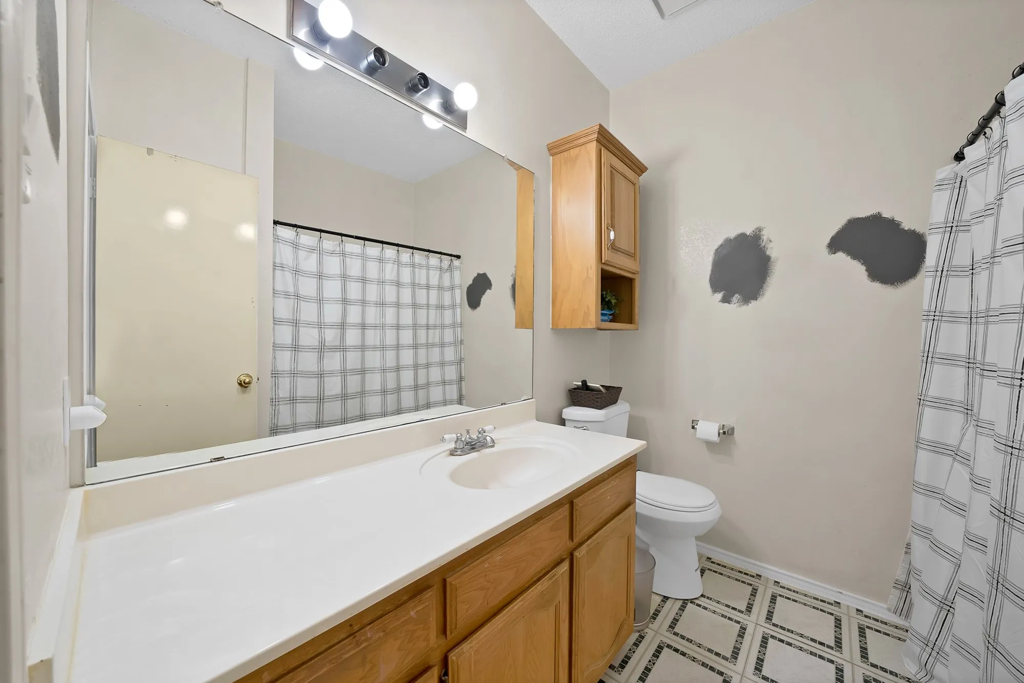 Spa-inspired bathroom featuring a wood-finish vanity with ample storage, white countertop, and large framed mirror with integrated lighting