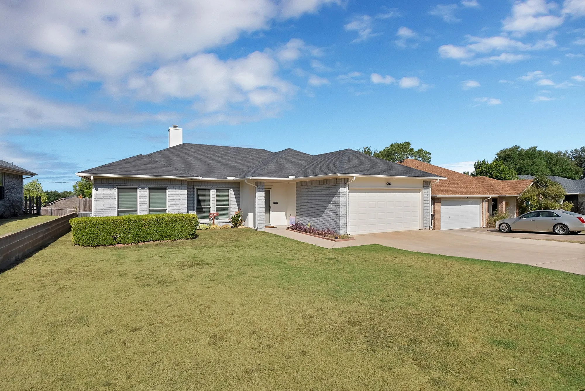 Contemporary brick exterior with a dark shingle roof, two-car garage, and a concrete driveway