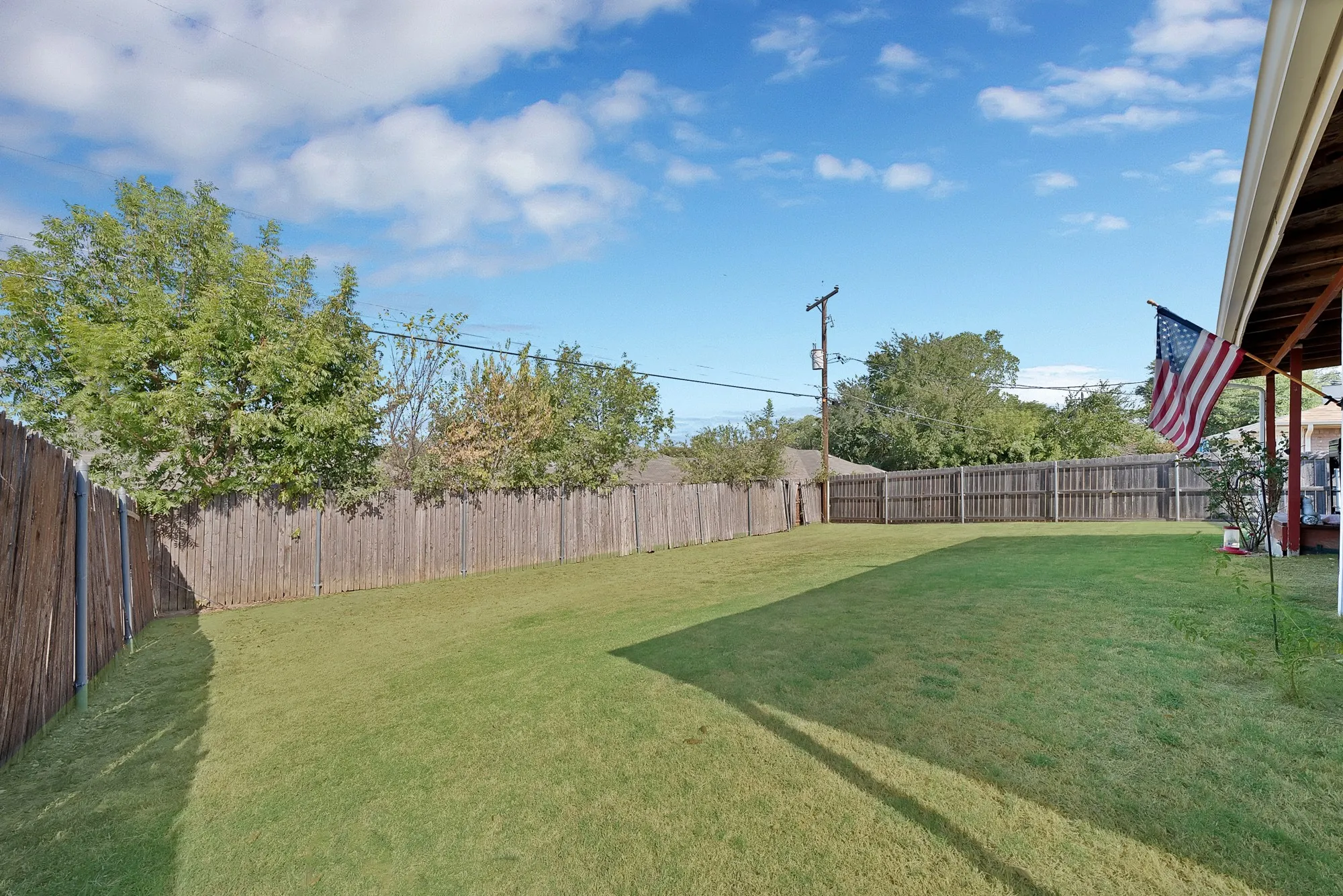 Expansive backyard featuring a manicured lawn and wood fencing