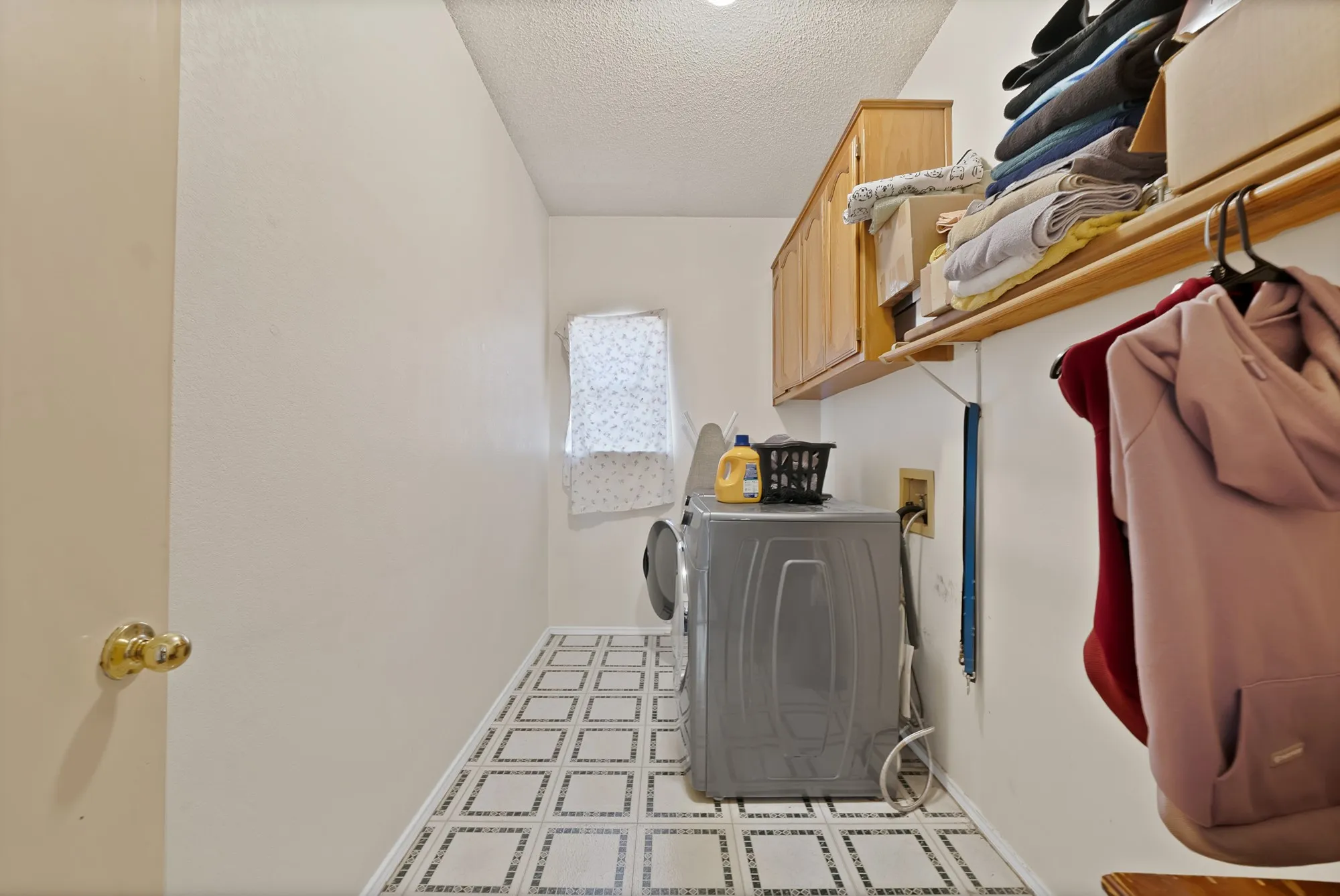Tile flooring with decorative square patterns, wood-finish cabinetry, and an integrated shelf