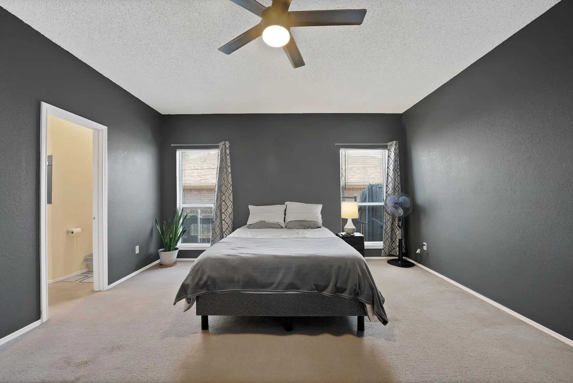 Carpeted bedroom with a ceiling fan