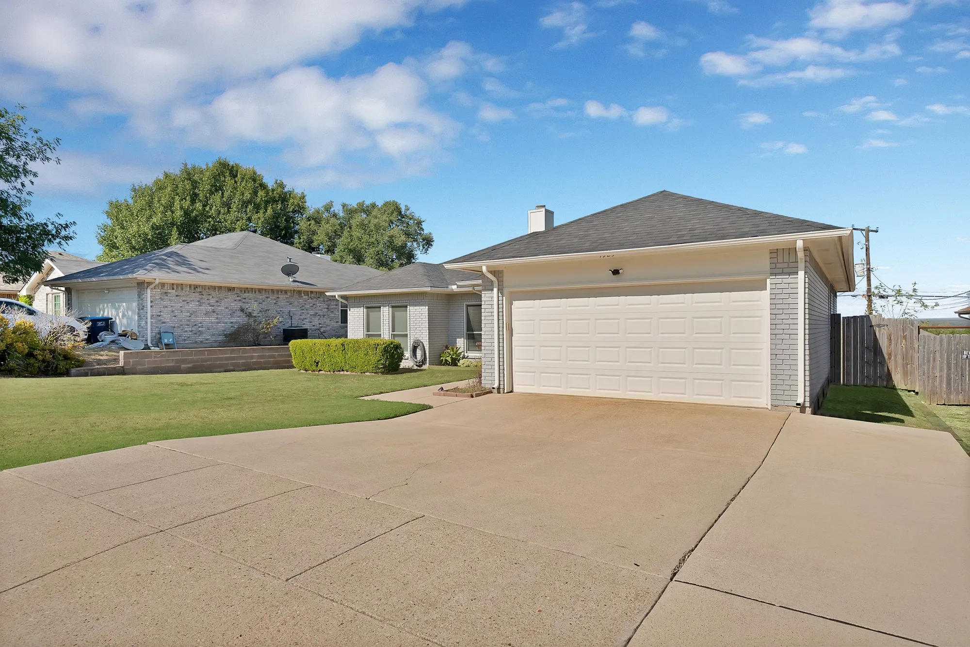 Attached garage with a panel door, concrete driveway, and brick-accented exterior