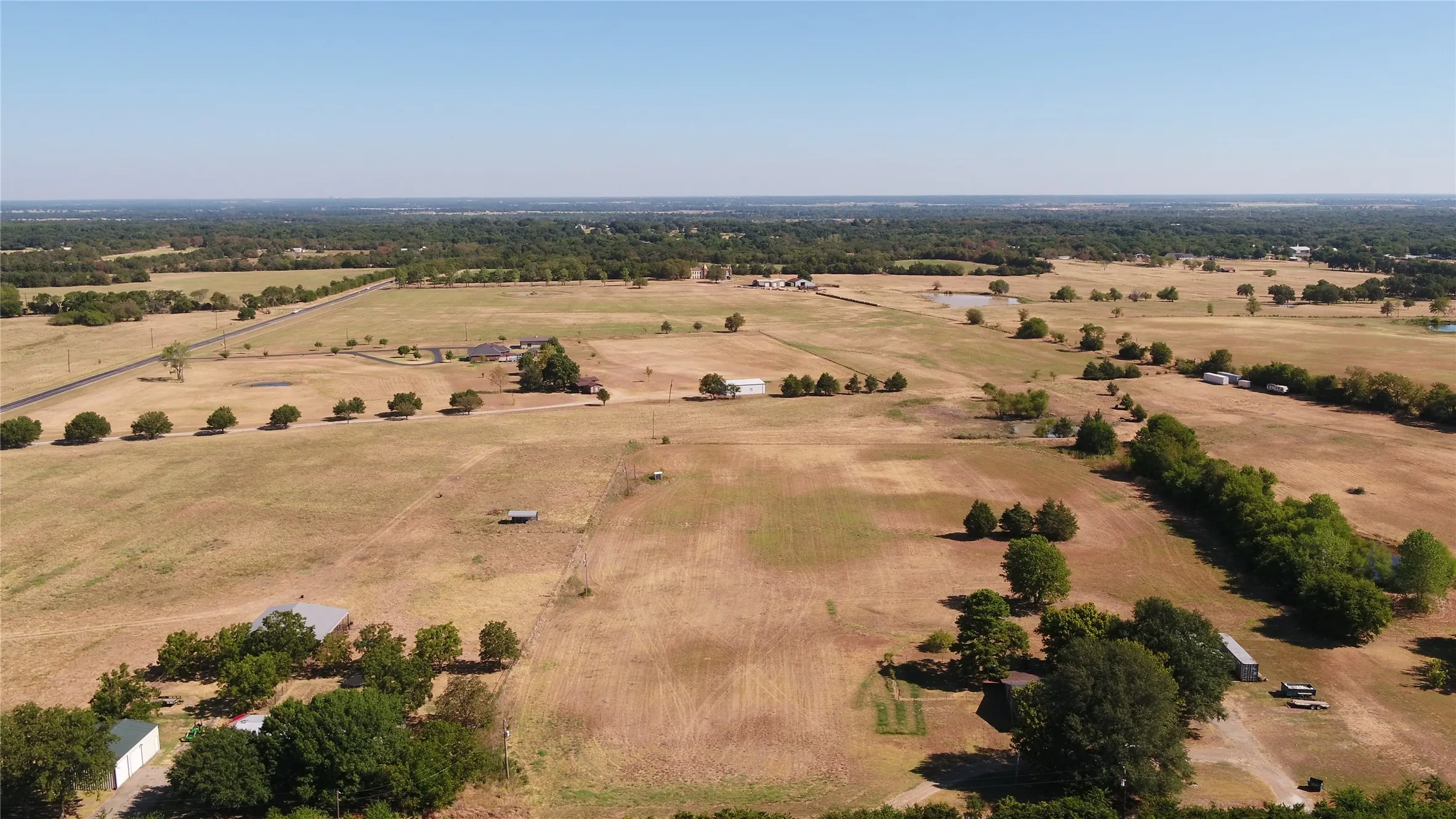 Expansive undeveloped land featuring mature trees and a clear sky