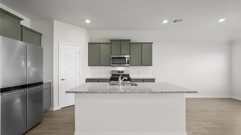 Kitchen featuring an island with a light-toned countertop, stainless steel appliances, and wood-finish flooring