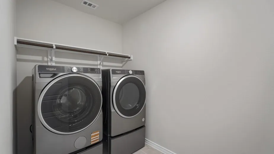 Dedicated laundry room featuring side-by-side front-load washer and dryer with pedestal bases, chrome rod shelving, recessed ceiling lighting, and neutral wall finishes