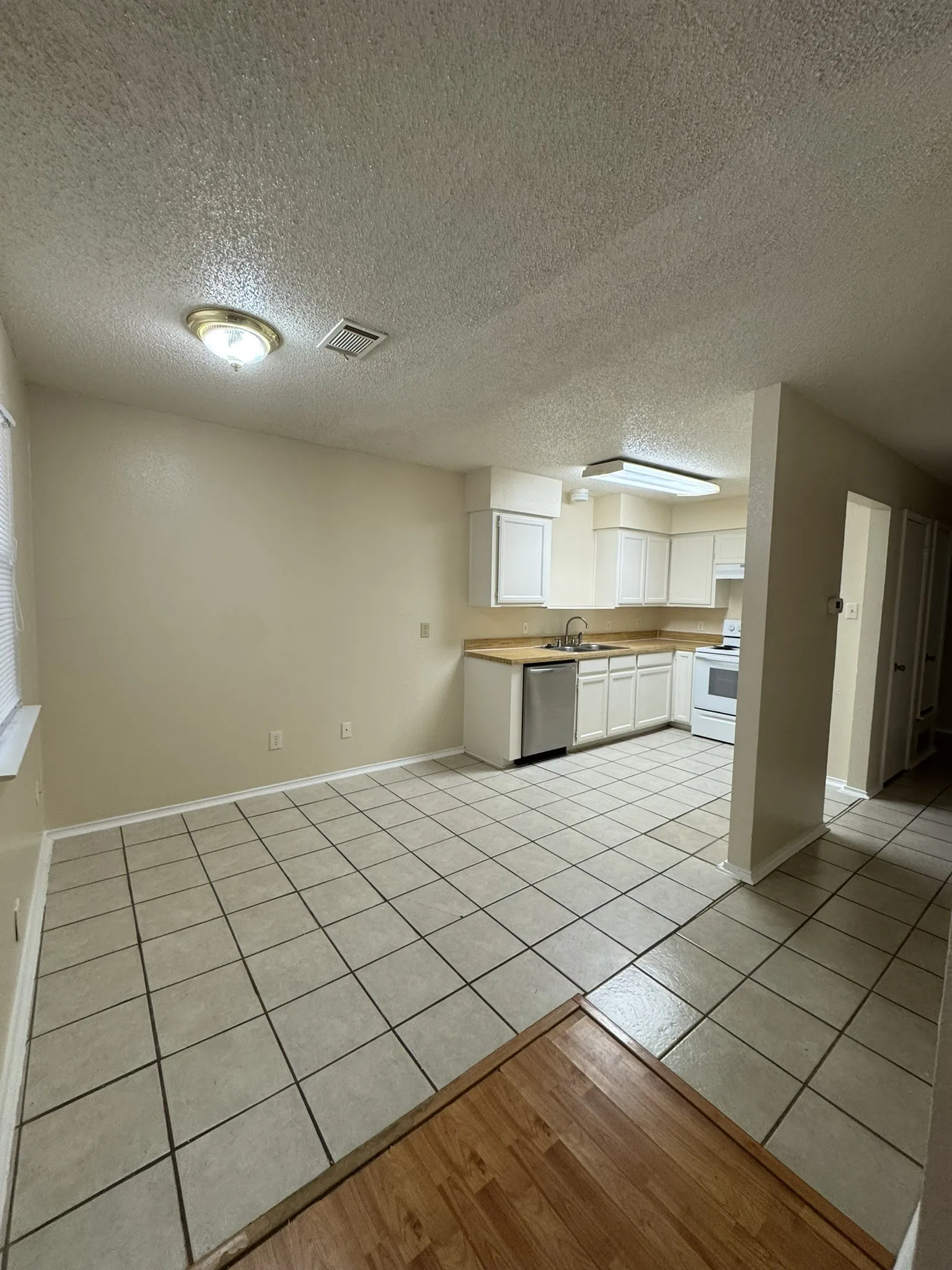 Kitchen with electric range, dishwasher, white cabinetry, light countertops, and a textured ceiling