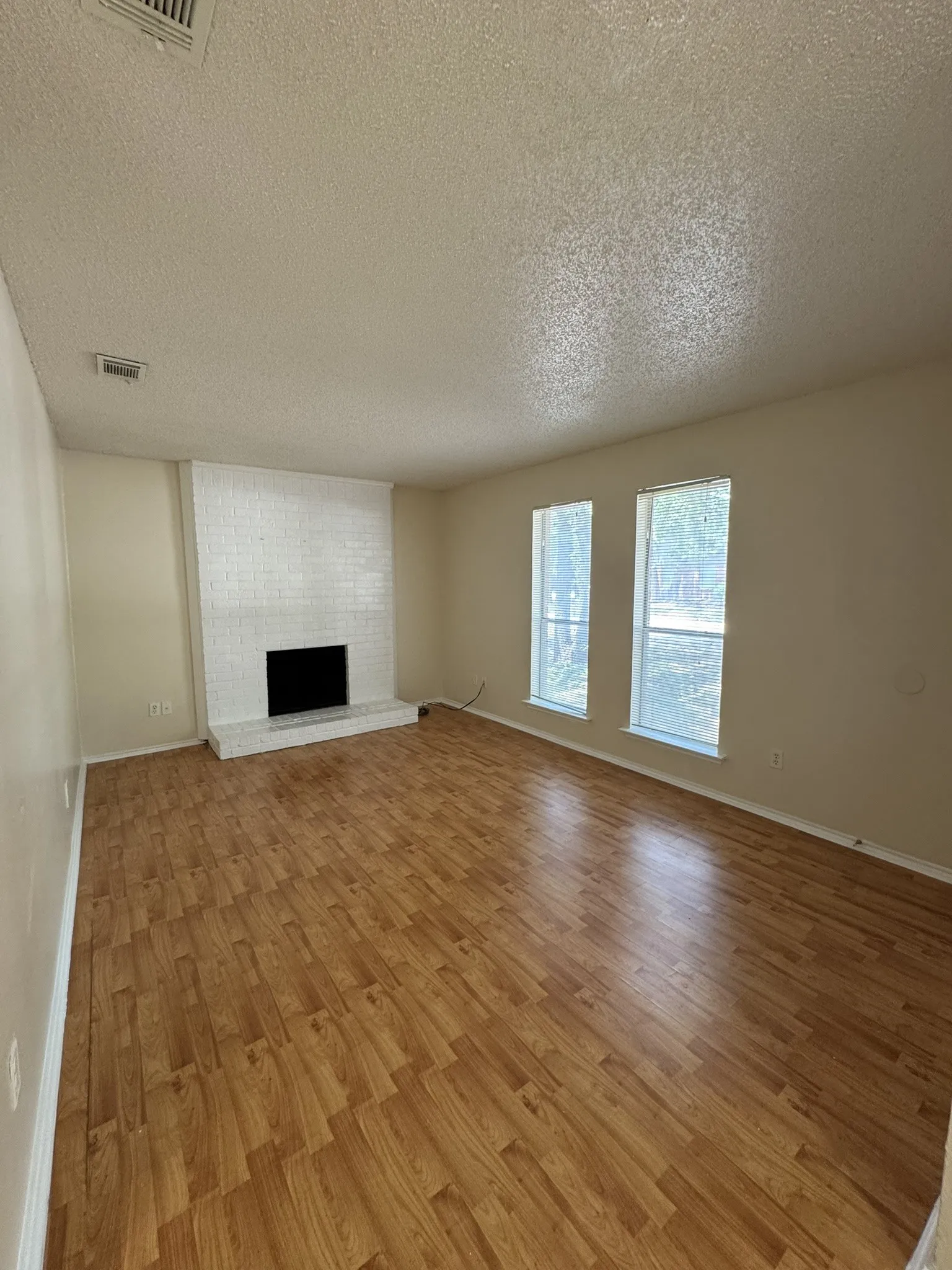 Unfurnished living room featuring a textured ceiling, light wood-style floors, and a fireplace