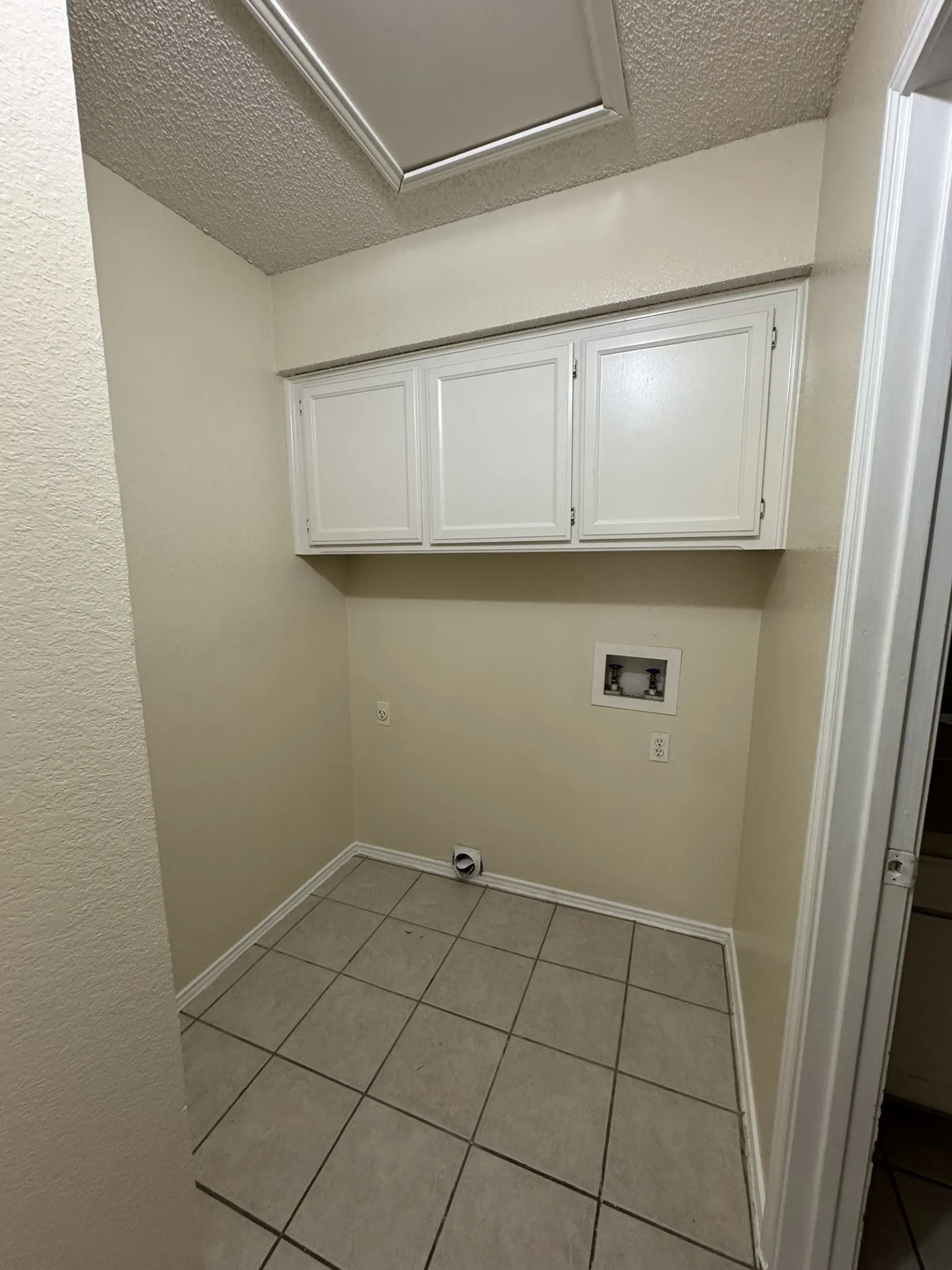 Laundry room featuring cabinet space, washer hookup, a textured ceiling, light tile patterned floors, and electric dryer hookup