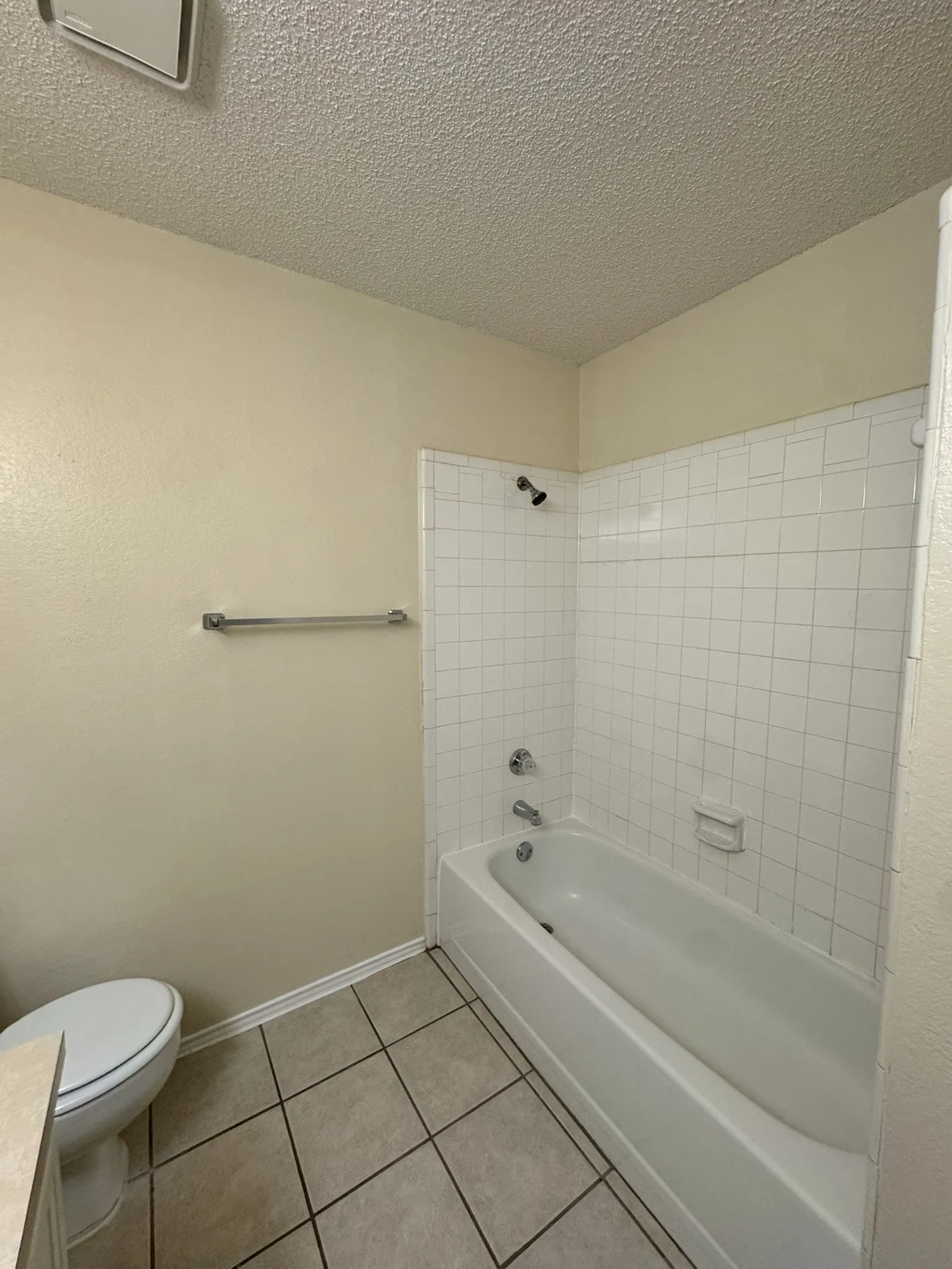 Full bathroom featuring a textured ceiling, tile patterned floors, vanity, and bathtub / shower combination