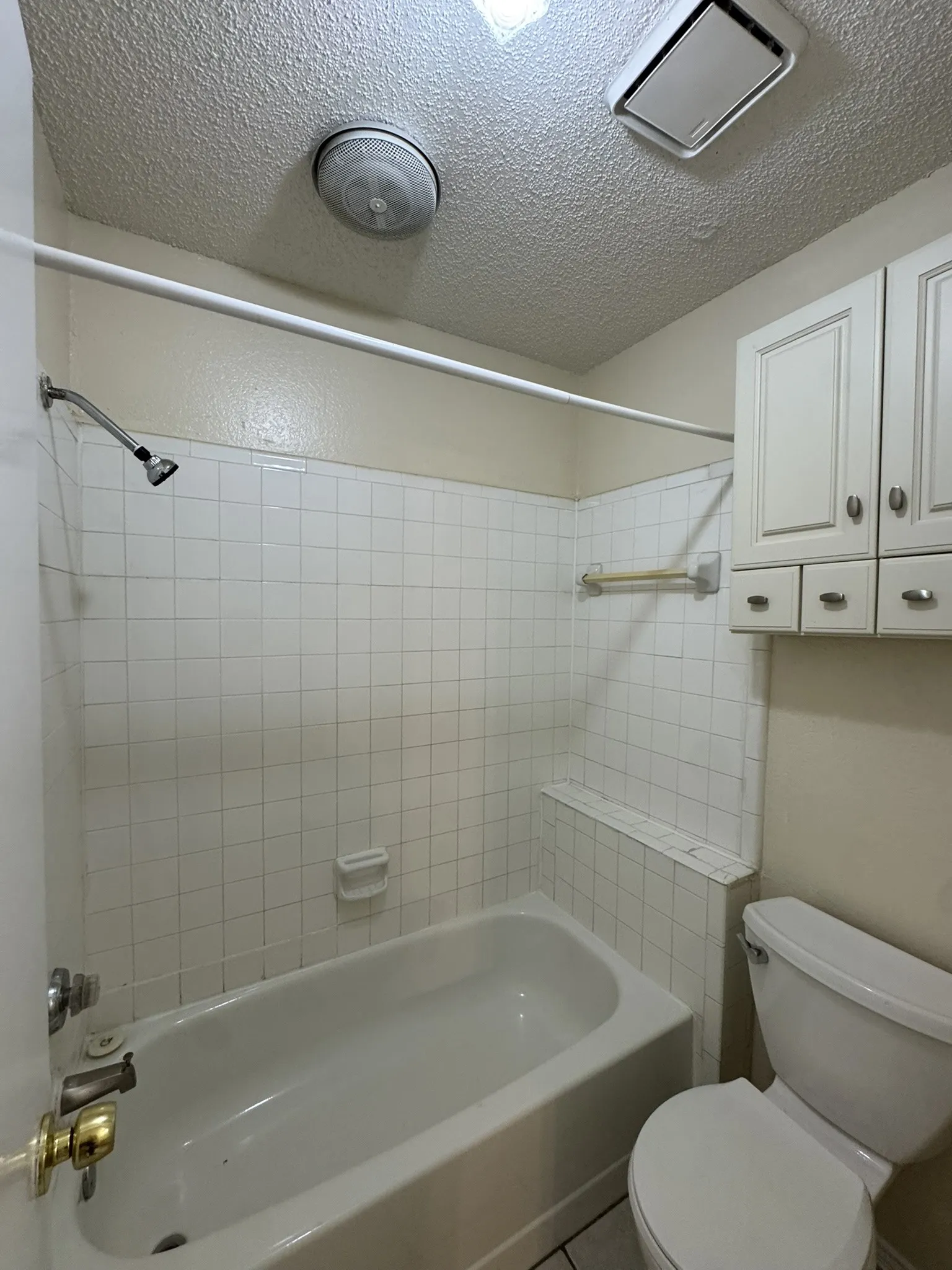 Full bath featuring a textured ceiling and shower / bathtub combination