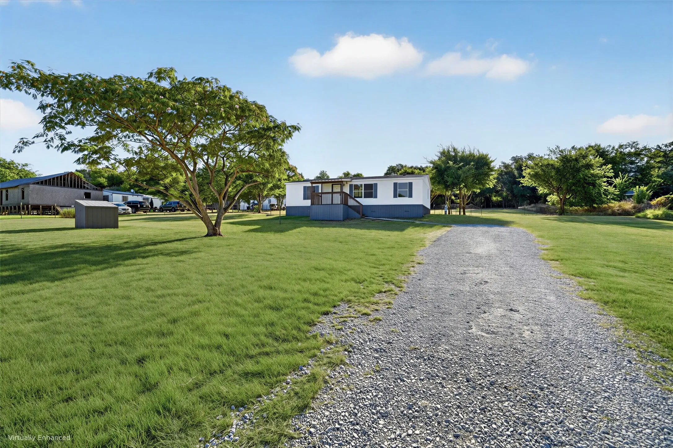 Gravel driveway leading to residence with white siding and dark trim. Grass & Landscape is AI