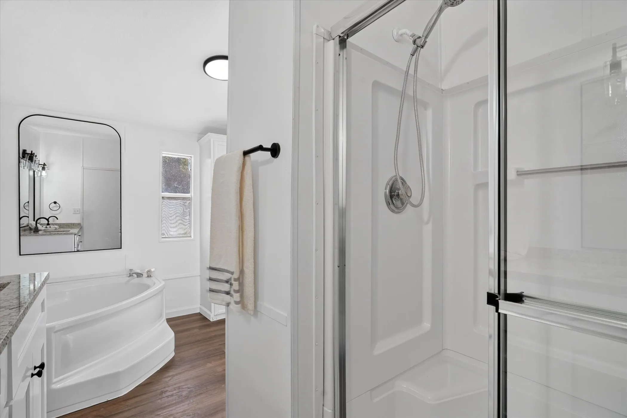 Walk-in shower with clear glass enclosure and handheld shower head