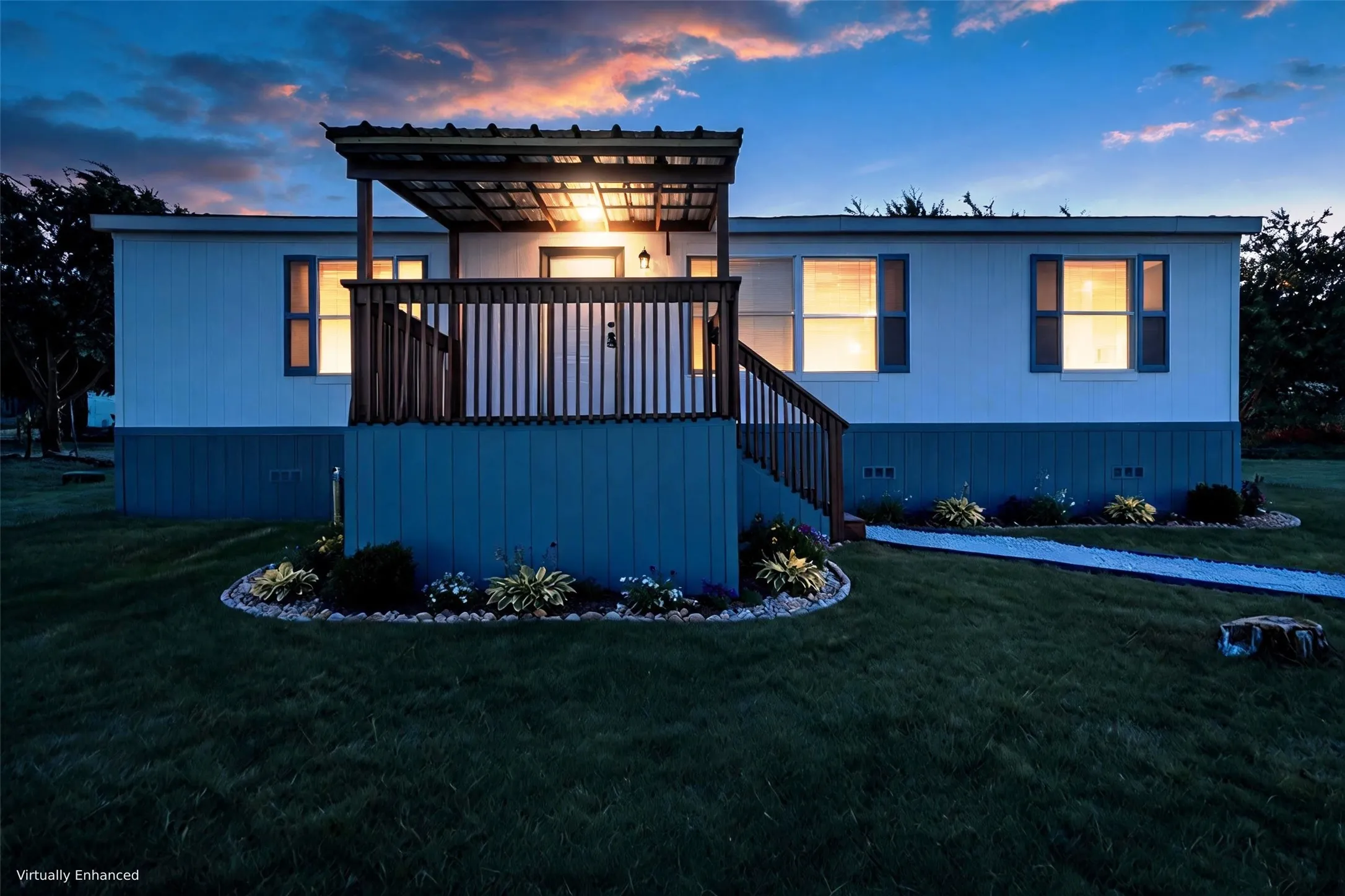 Front porch with a metal roof and wood railing, exterior siding with a contrasting base, and landscaped garden beds