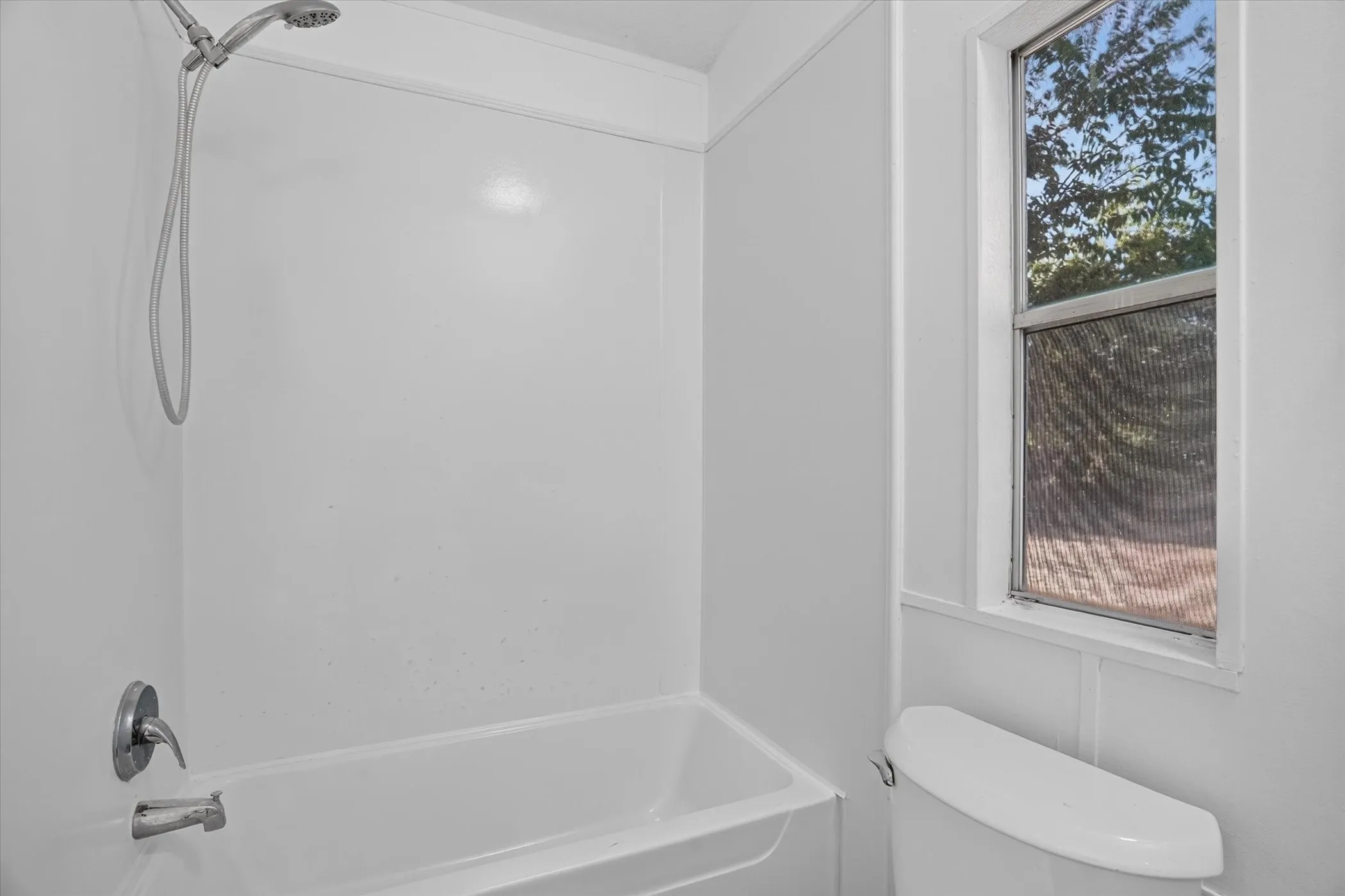 White tub and shower combination with chrome fixtures