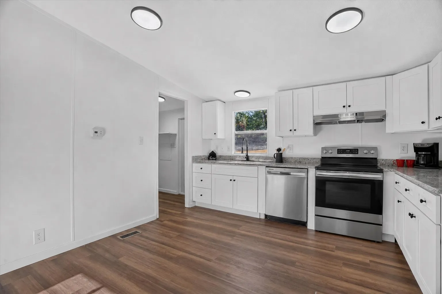 Kitchen featuring wood-finish flooring, white cabinetry, a stainless steel range, and a stainless steel dishwasher