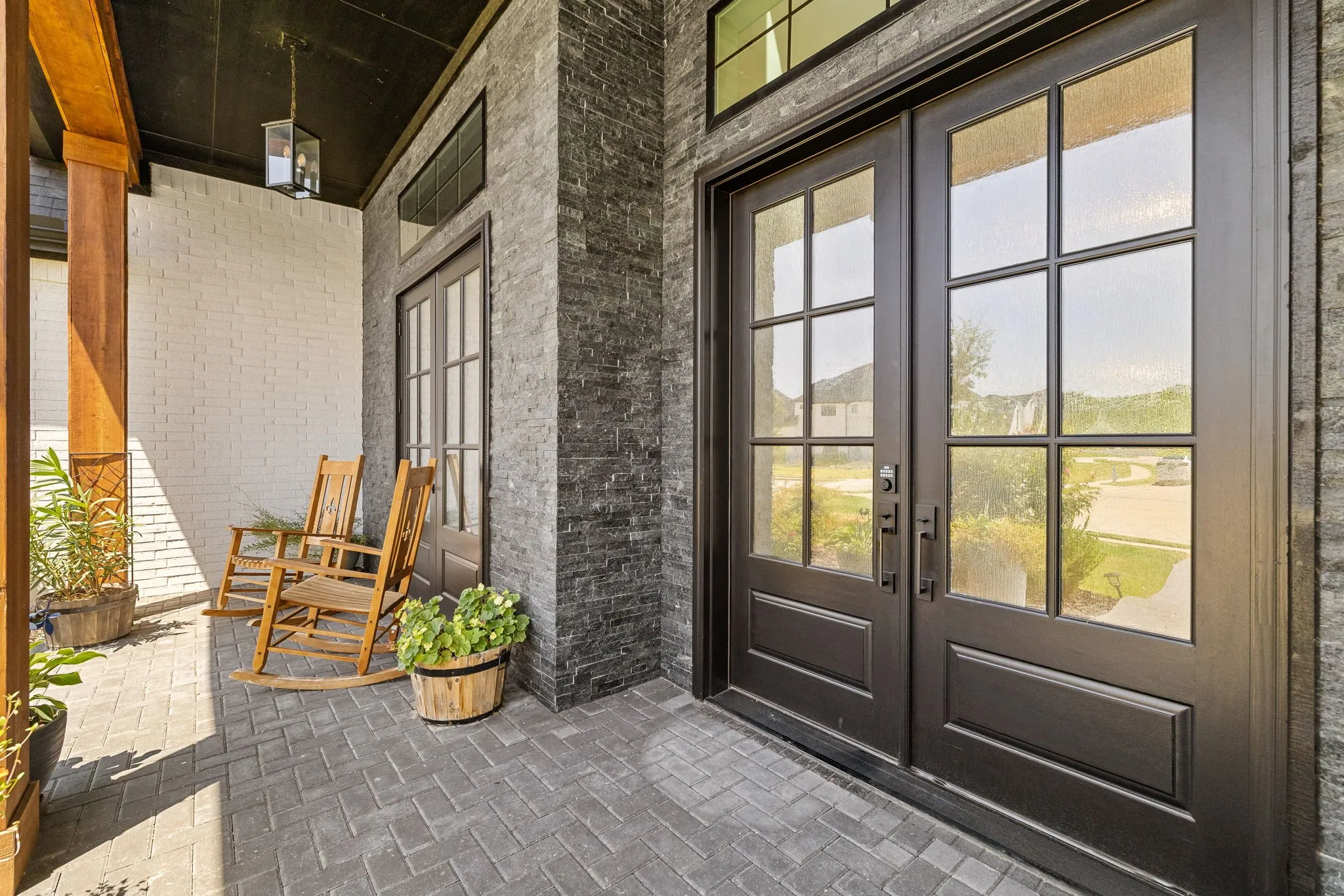 Double-door entry with divided lites, framed by stacked stone veneer and painted brick