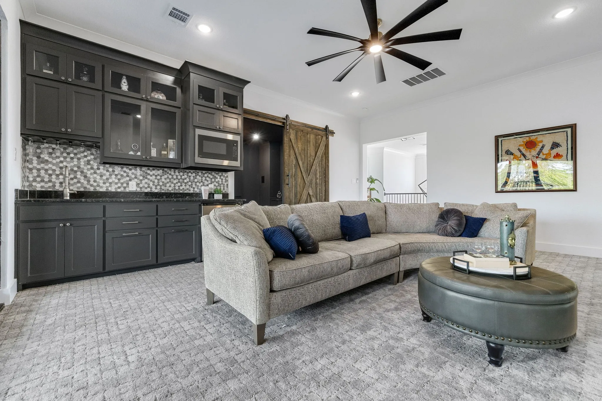Built-in wet bar with dark cabinetry, mosaic tile backsplash, and stainless steel microwave