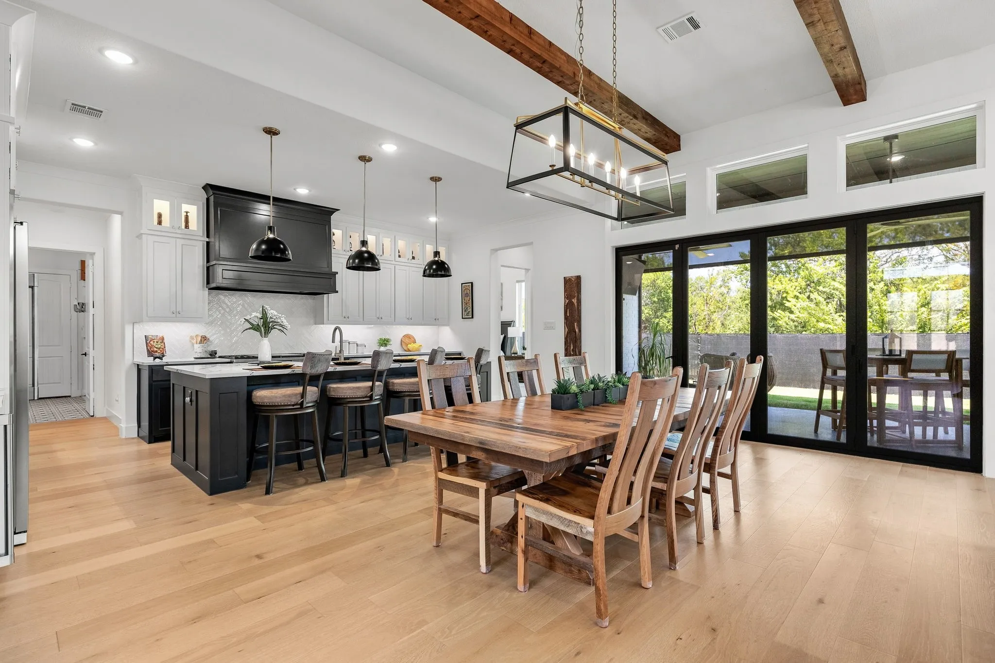 Spacious open-concept layout with wood-finish flooring, vaulted ceilings with exposed beams, and a kitchen island with seating