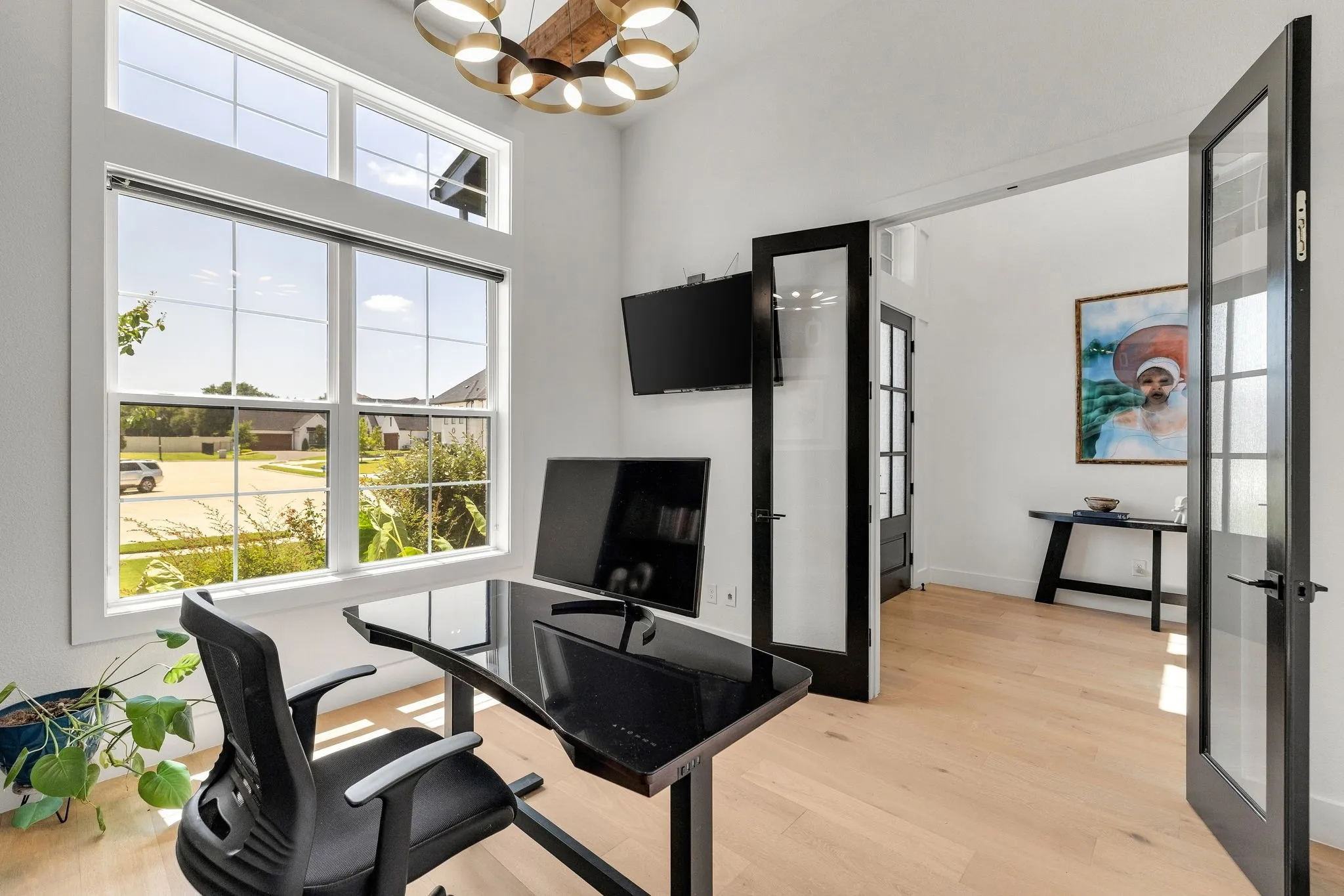 High ceilings with an architectural light fixture, wood-finish flooring, and black-framed French doors