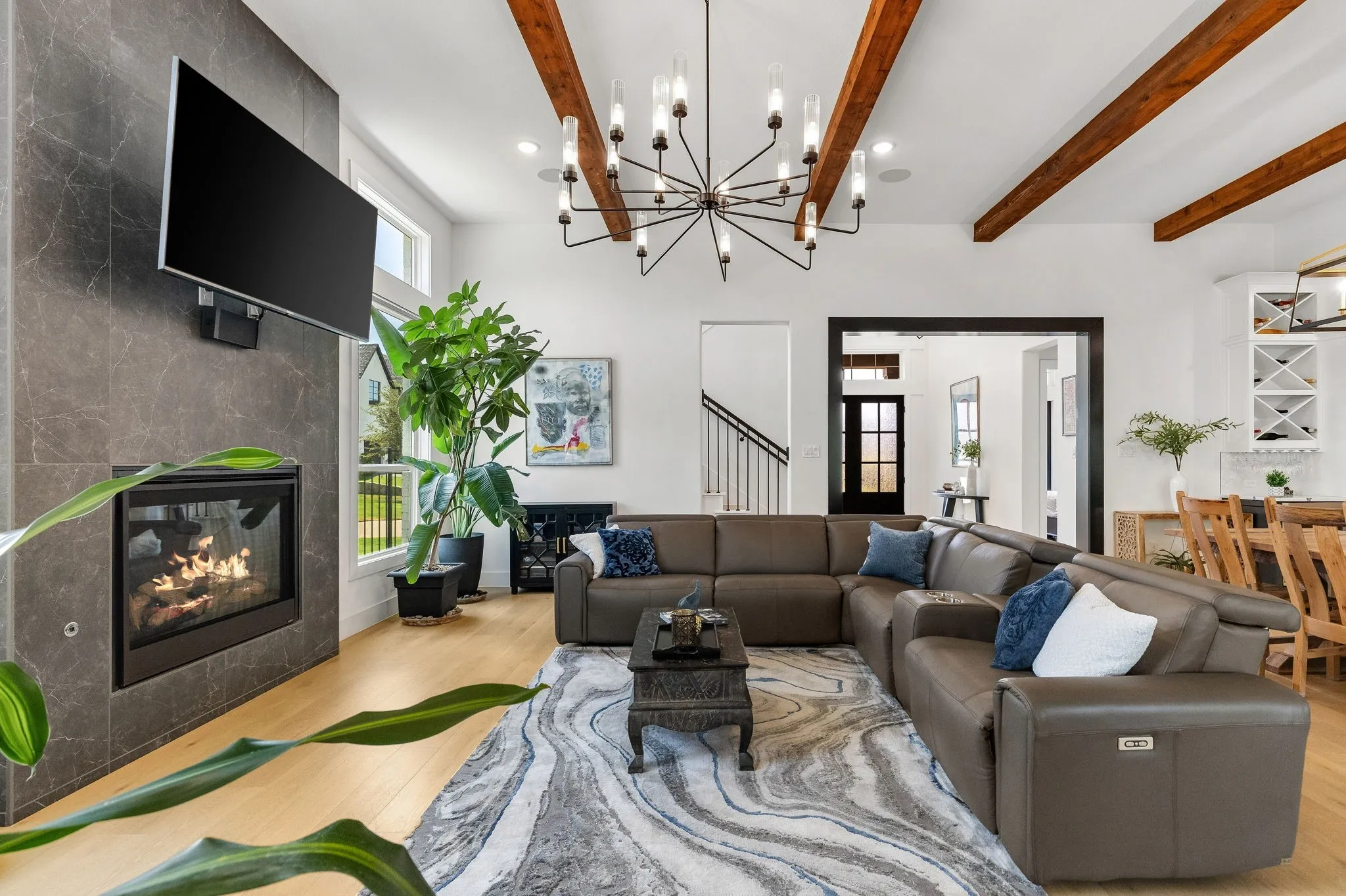 Open-concept living room featuring a curved sectional sofa arrangement, wood-finish flooring, and a geometric area rug